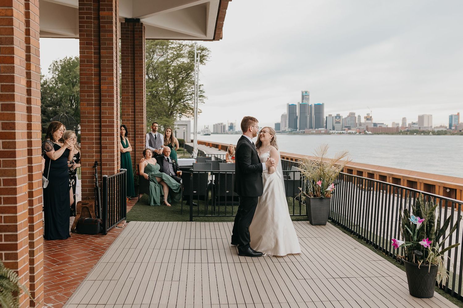 Wedding celebration on waterfront terrace with city skyline view.