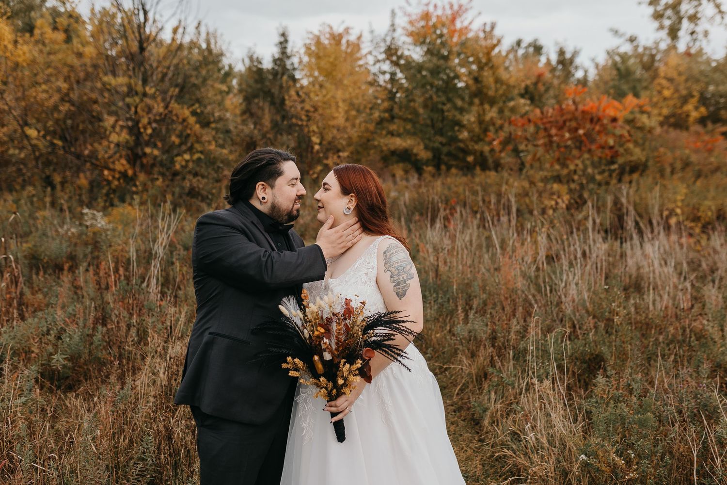 Autumn wedding portrait in a field with fall foliage and warm colors.