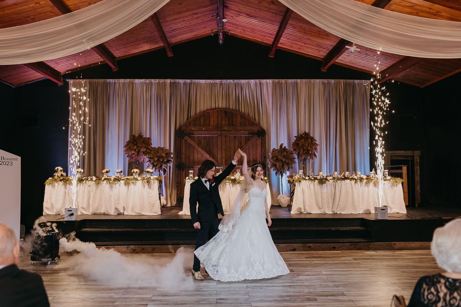 First dance in elegant reception hall with draped fabric and rustic details.