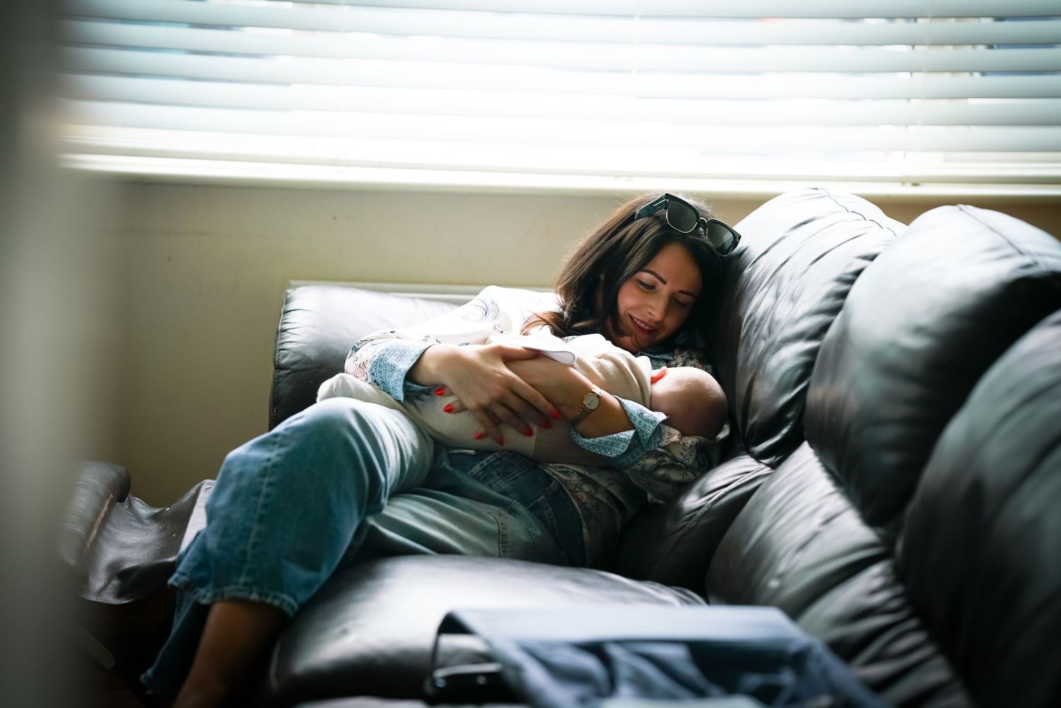 Mother breastfeeding her newborn baby on the sofa during a natural, documentary family photography session at home.