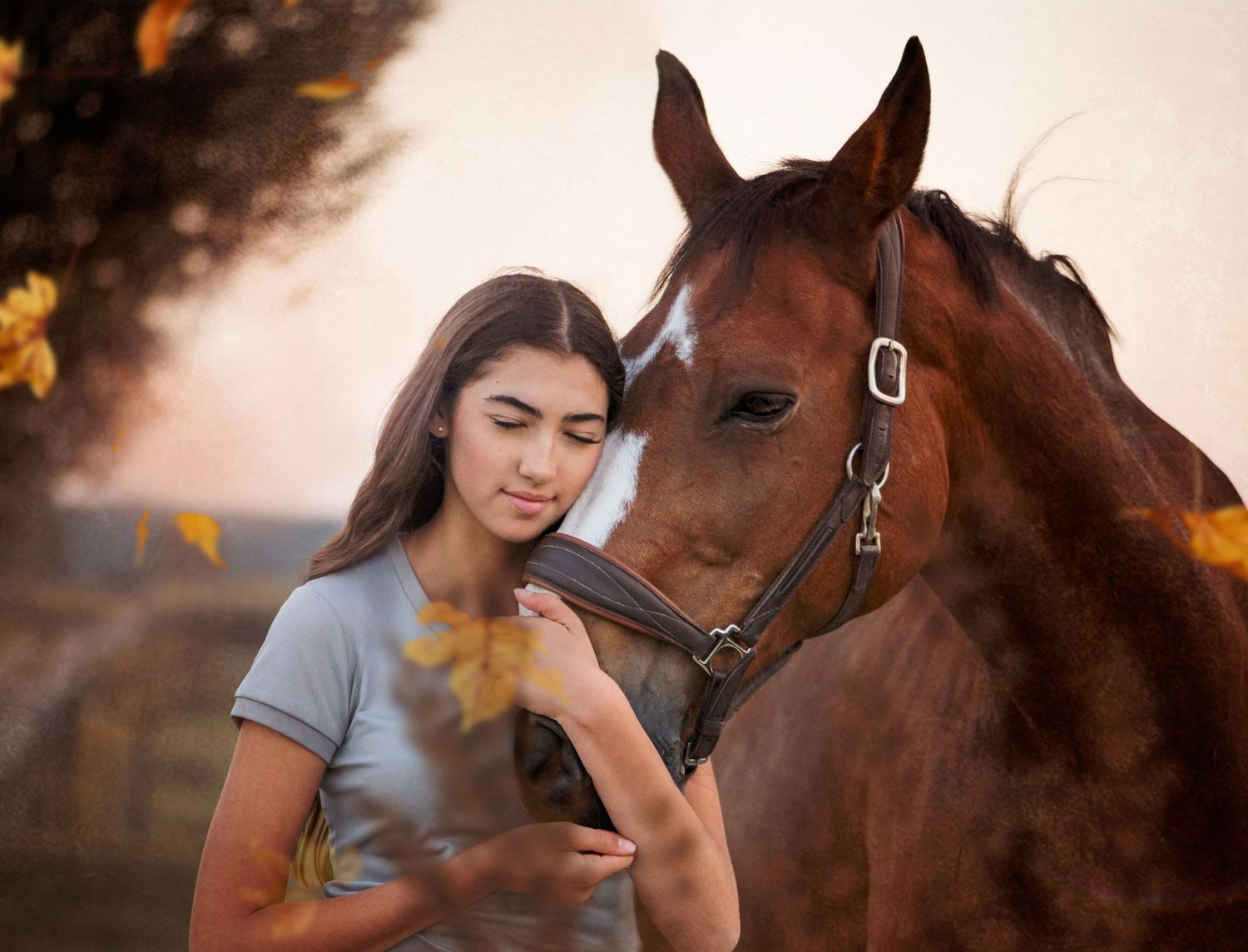 Young woman in gray shirt tenderly bonding with a chestnut horse outdoors among golden autumn leaves.