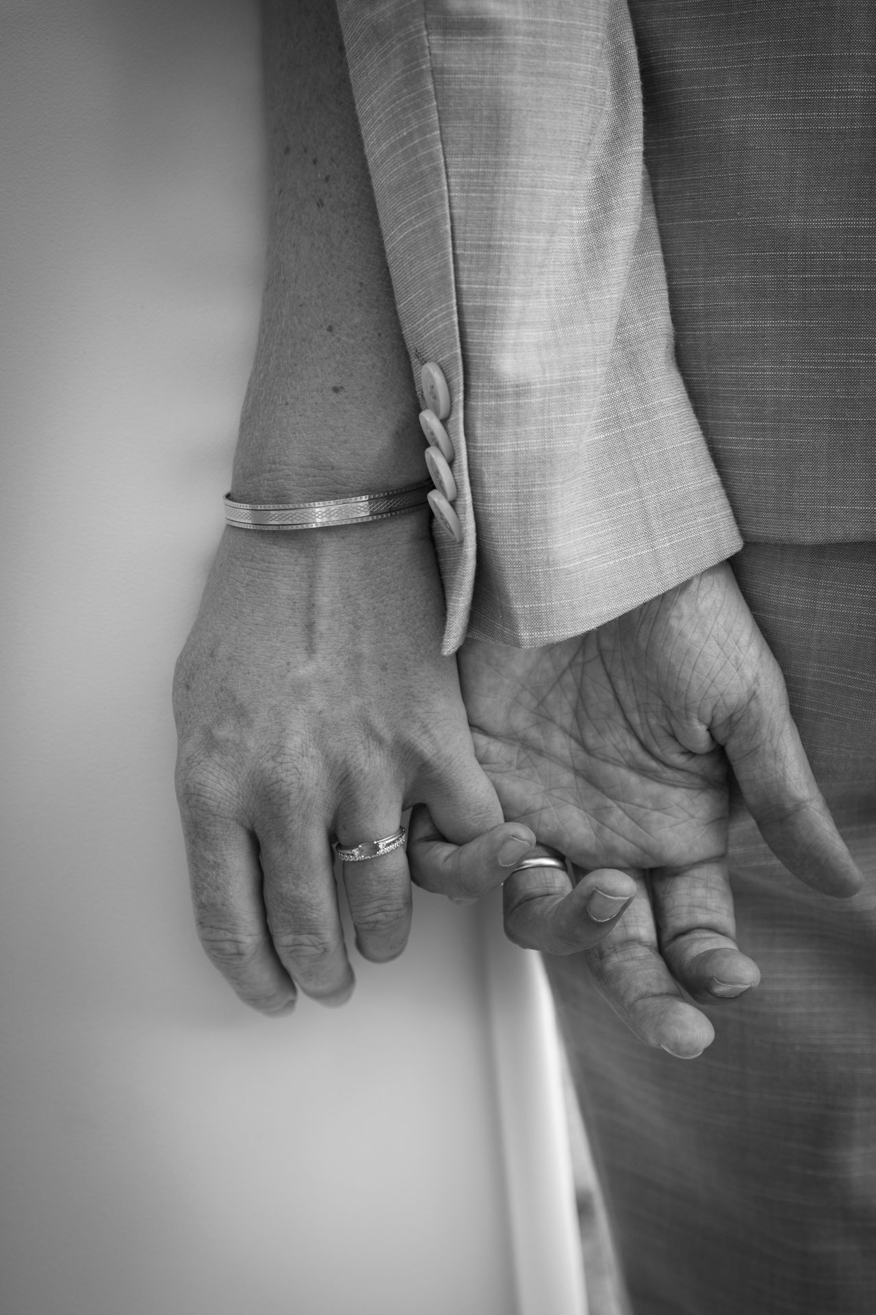 Mains enlacées d’un couple de mariés en noir et blanc, bracelet et alliance visibles, séance mariage à Lyon