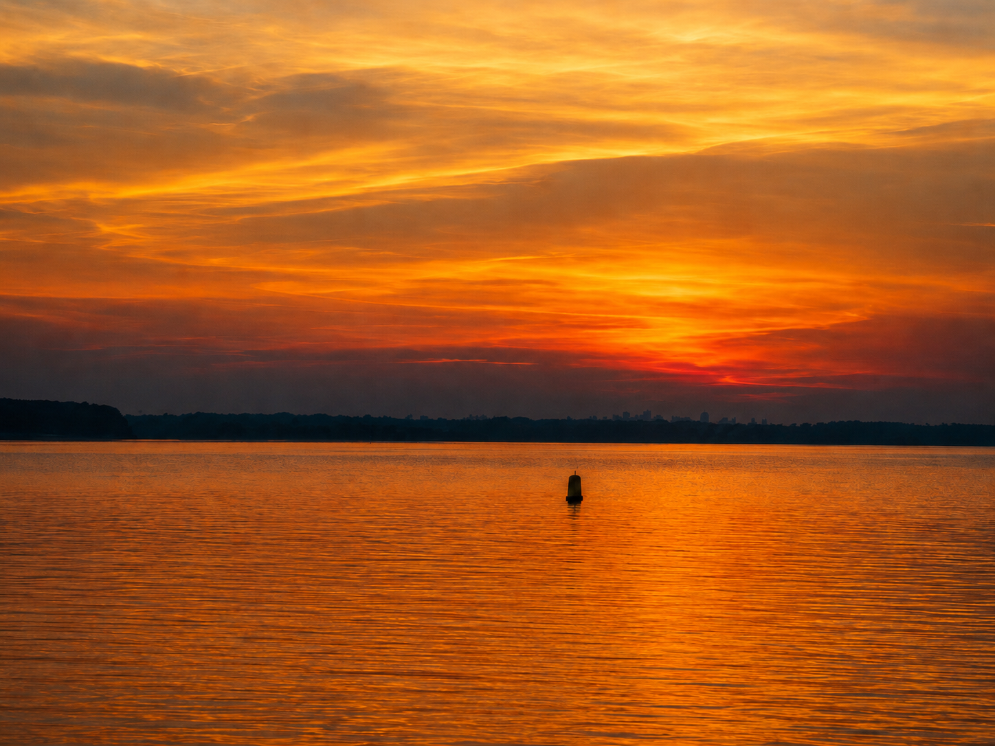 Orange and red sunset reflecting across calm water beneath a glowing sky.