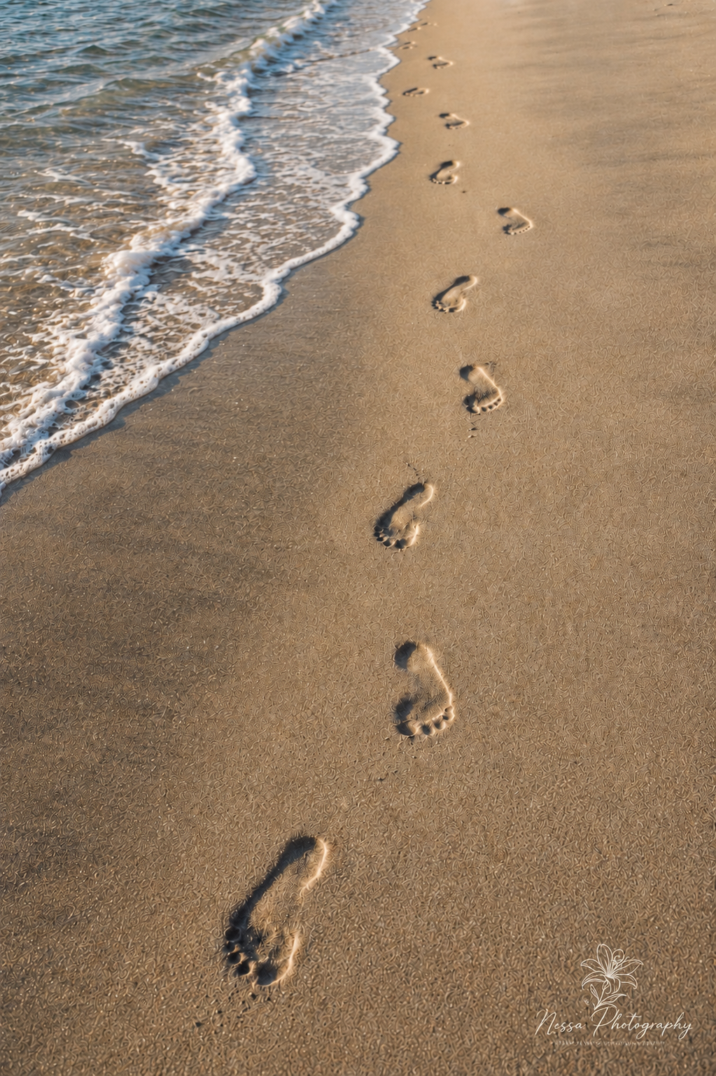 Footprints in sand
Footprints leading along wet sand beside gentle ocean waves.