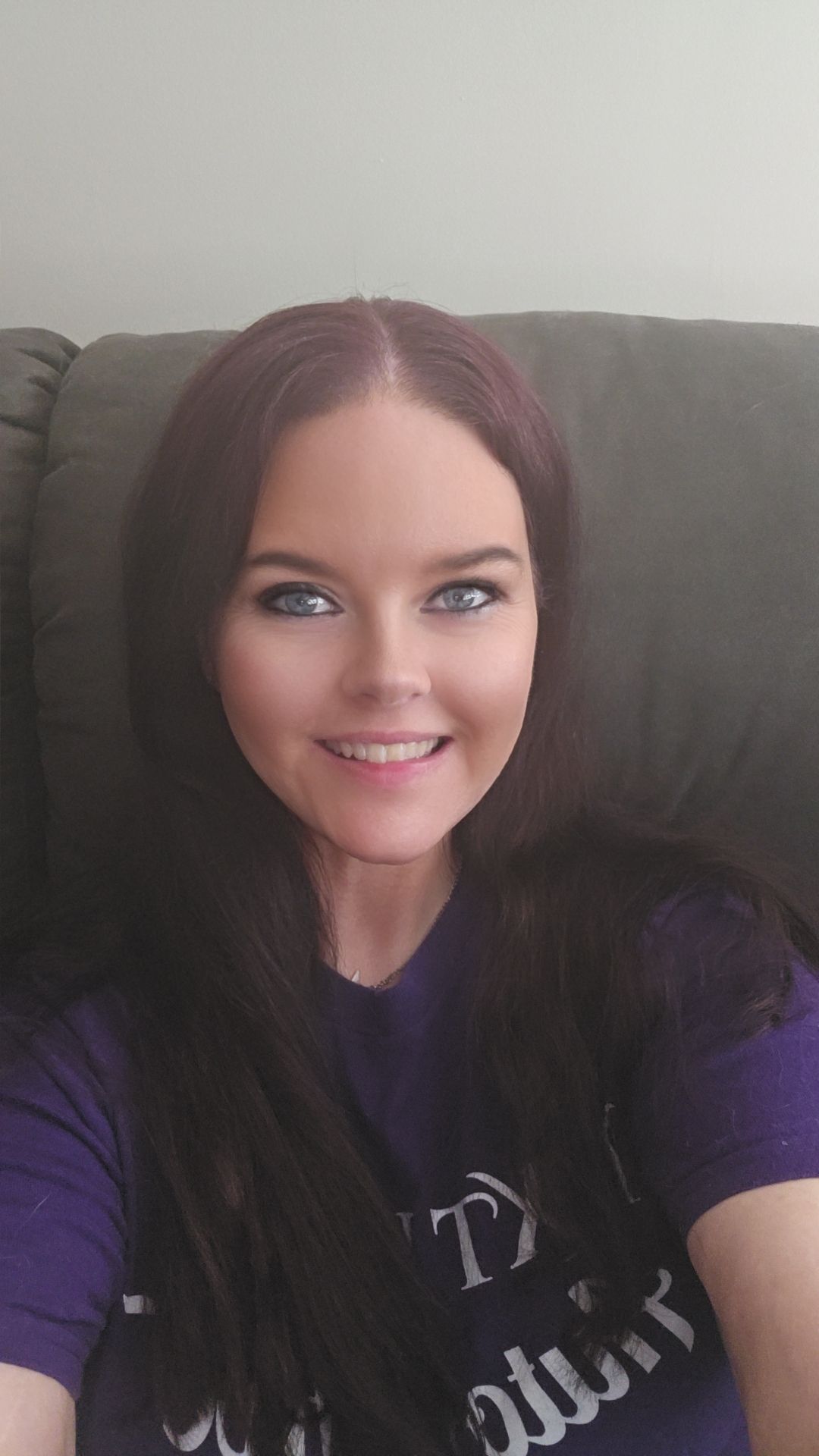Casual indoor portrait of a smiling woman with long dark hair looking at the camera.
