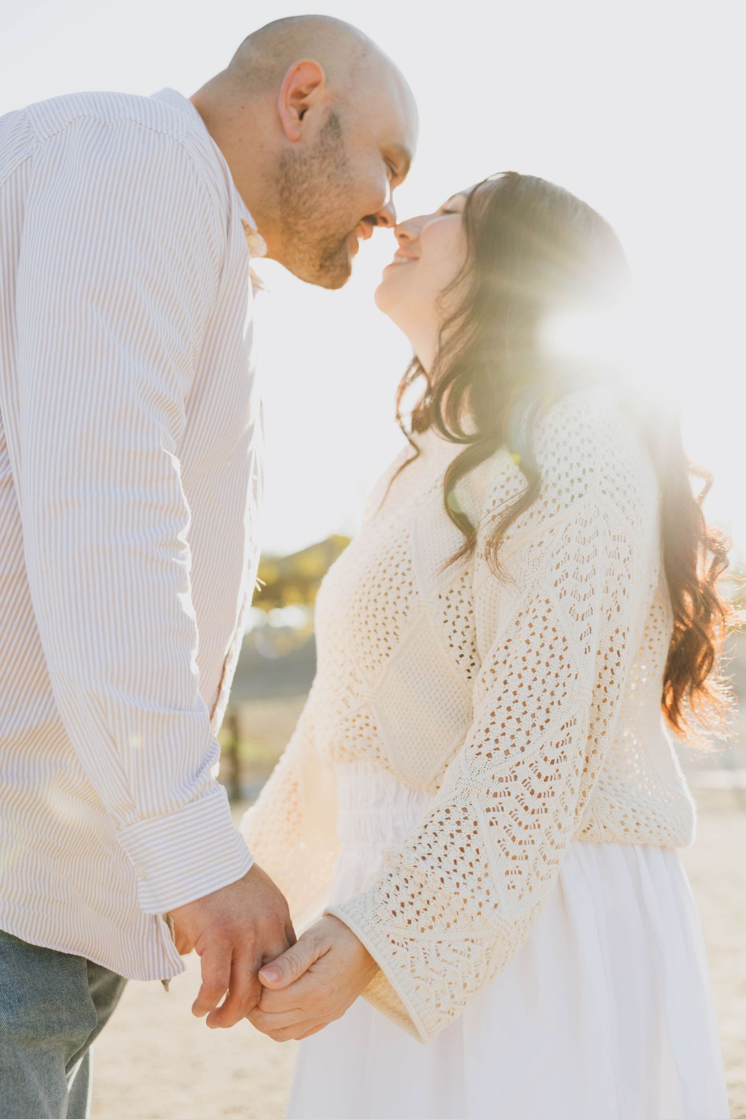 Husband and wife touching noses and holding hands in golden sunset light during a San Diego couples photoshoot