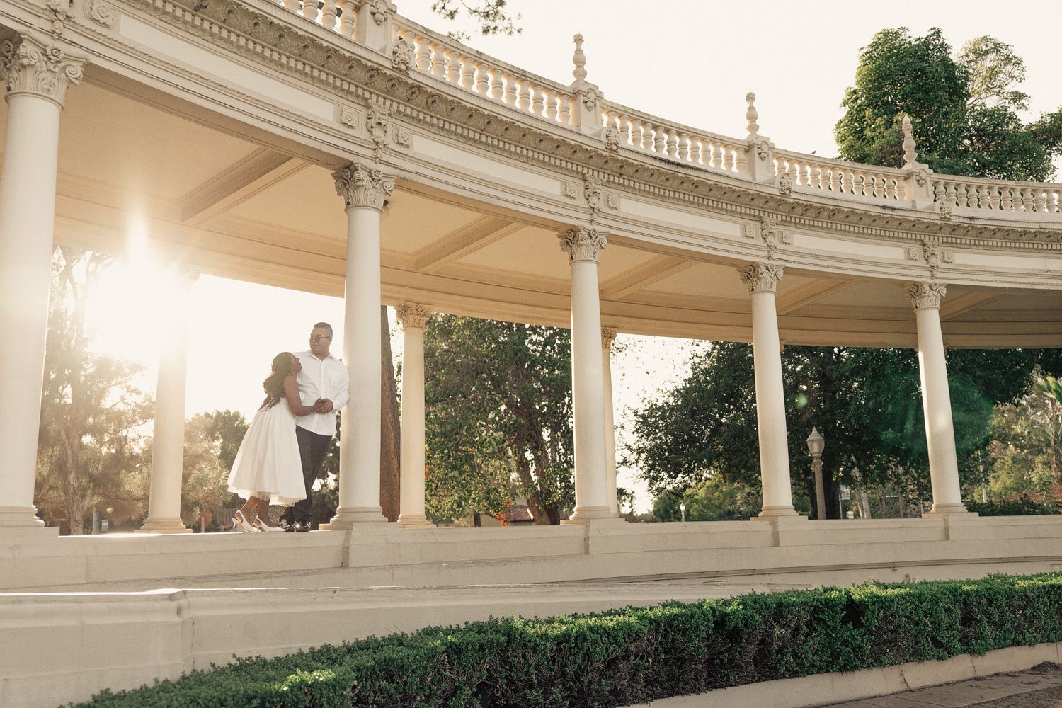 Couple embracing beside a column of a classical colonnade in San Diego at golden hour