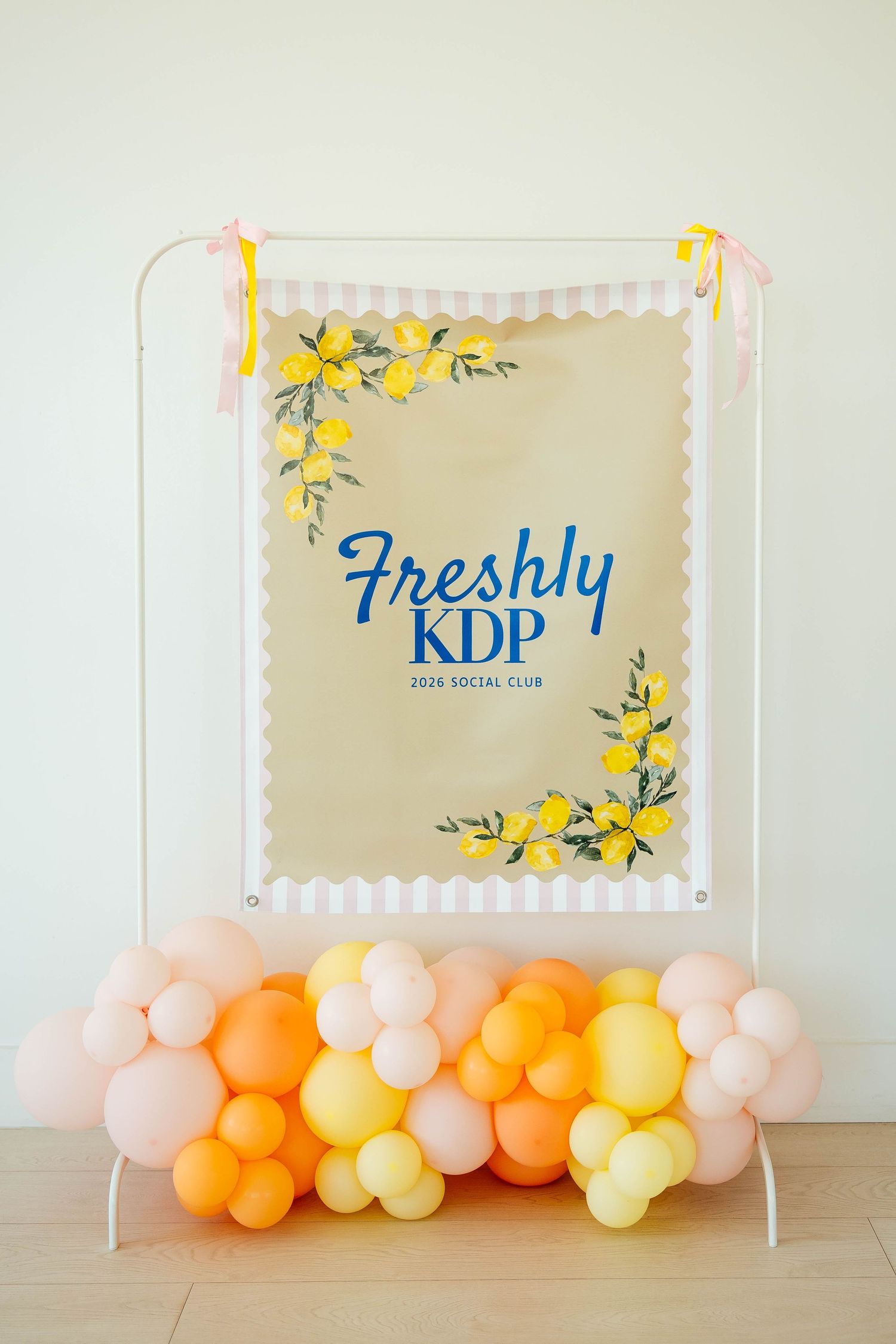 Freshly KDP 2026 Social Club banner with yellow floral accents displayed with pastel balloon arrangement.