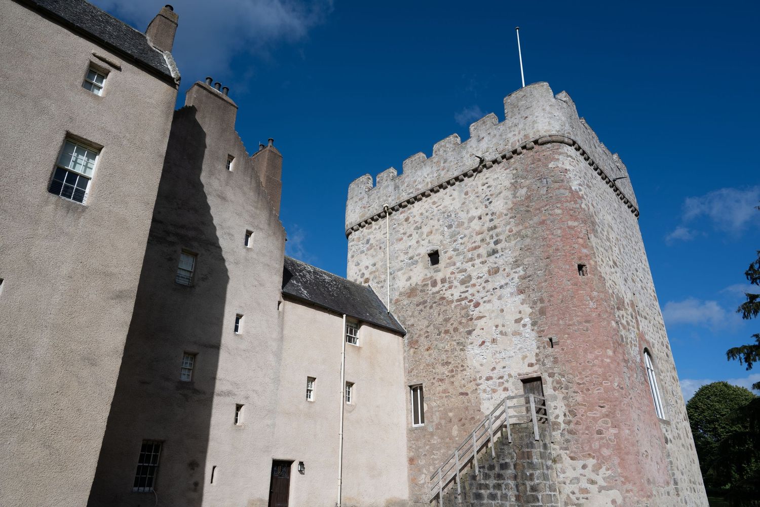 Historic Scottish castle with a tall stone tower and battlements against a clear blue sky.