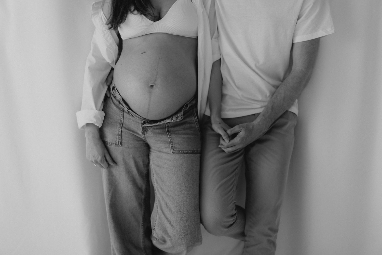 A black and white maternity photo of a couple standing together showcasing a pregnant belly.sesje zdjęciowe Rybnik, Wodzisław Śląski