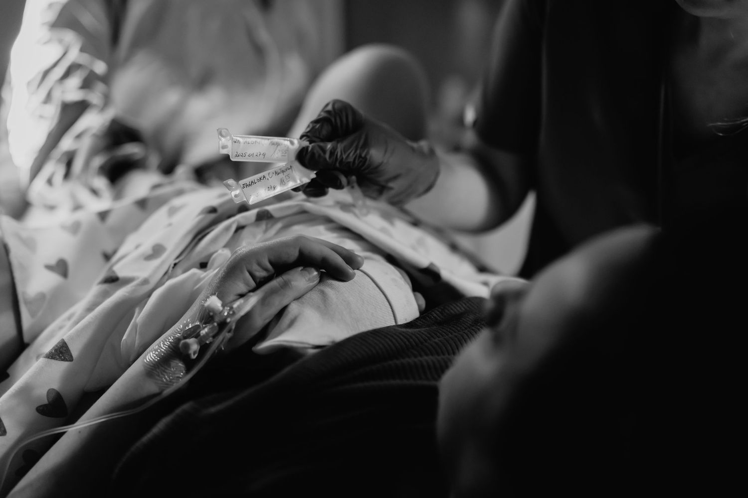 Black and white photo of a newborn baby being held in a hospital, wrapped in a blanket after sesje zdjęciowe Rybnik, Wodzisław Śląski
