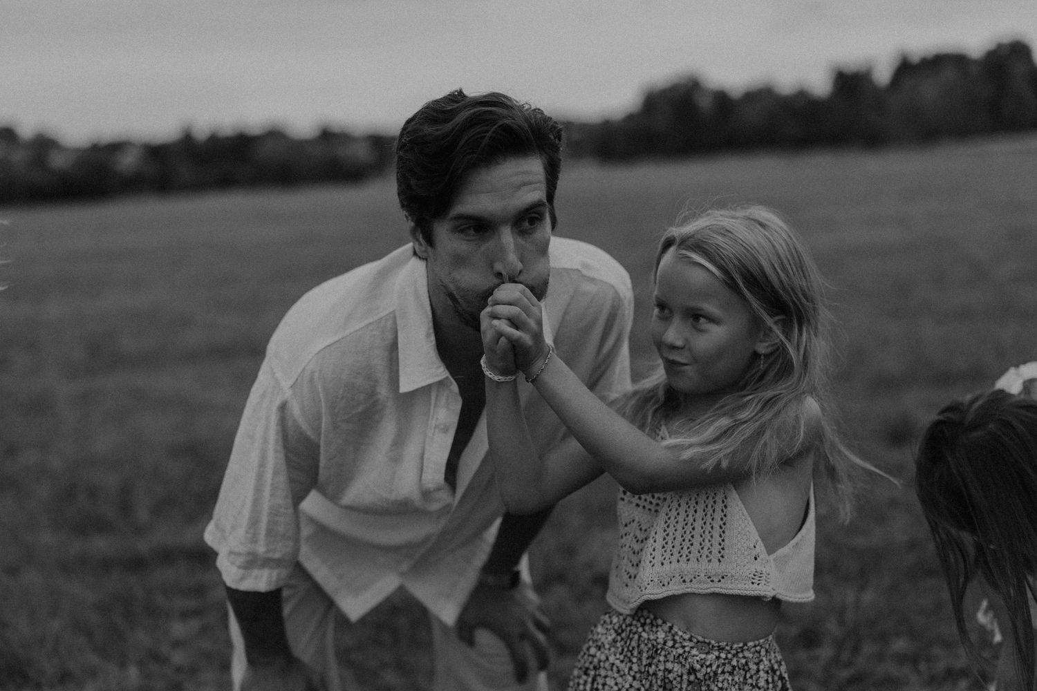 Black and white photo of a man and young blonde girl sharing a tender moment in an open field.
