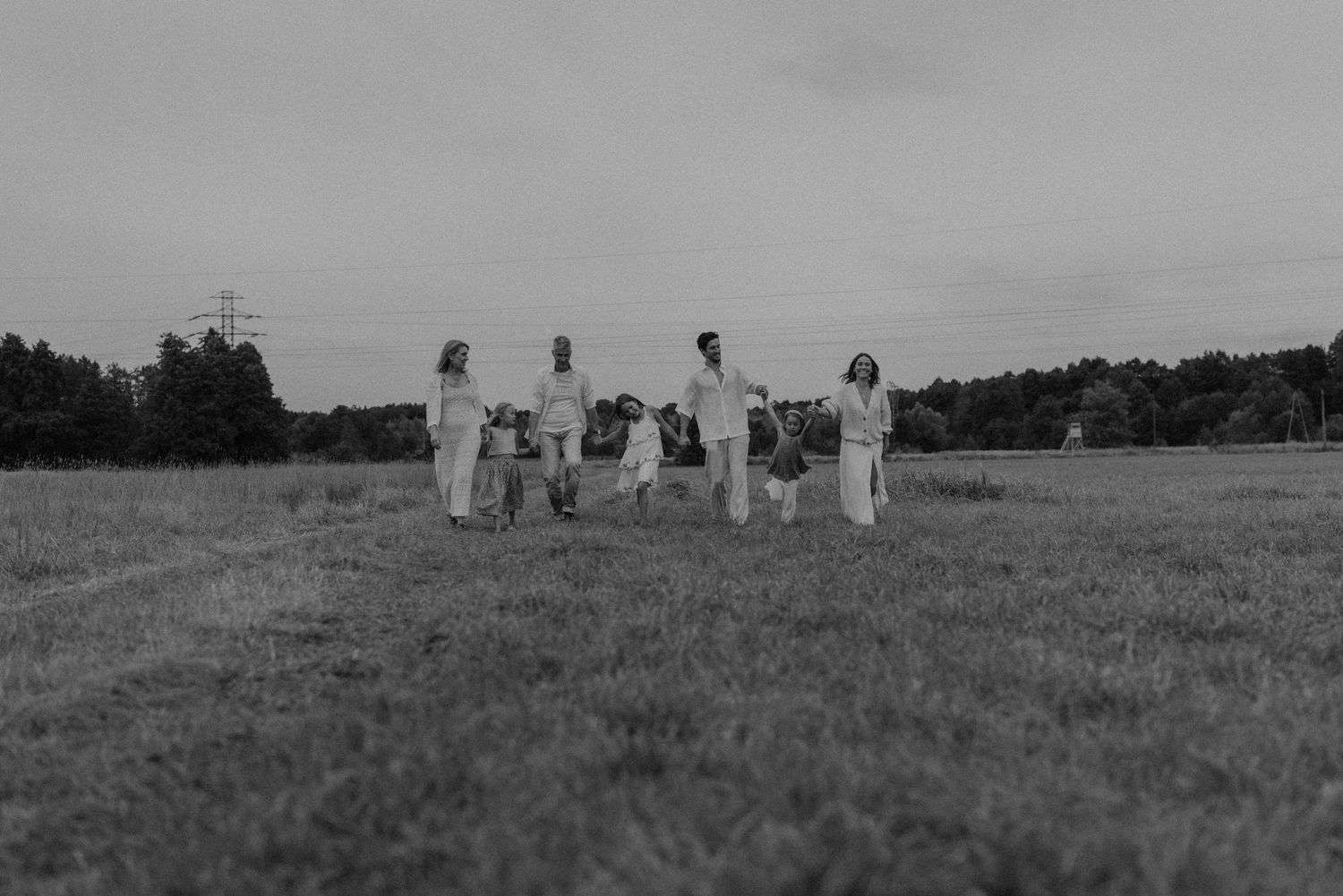 Group of people in white outfits standing in a field holding hands in black and white photo.