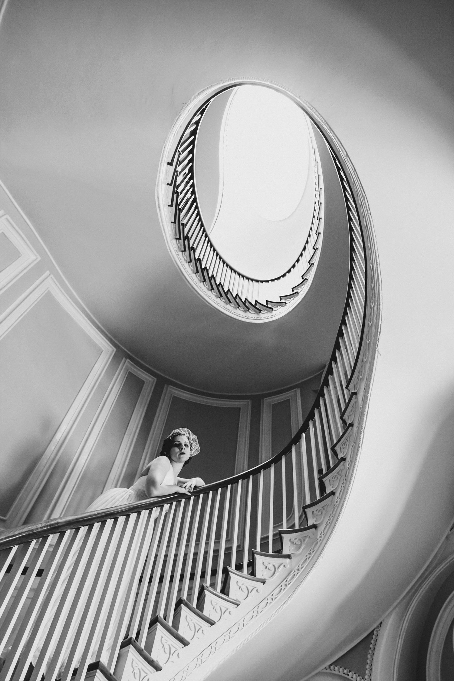Black and white view of a woman on a spiral staircase, shot from above in dramatic light