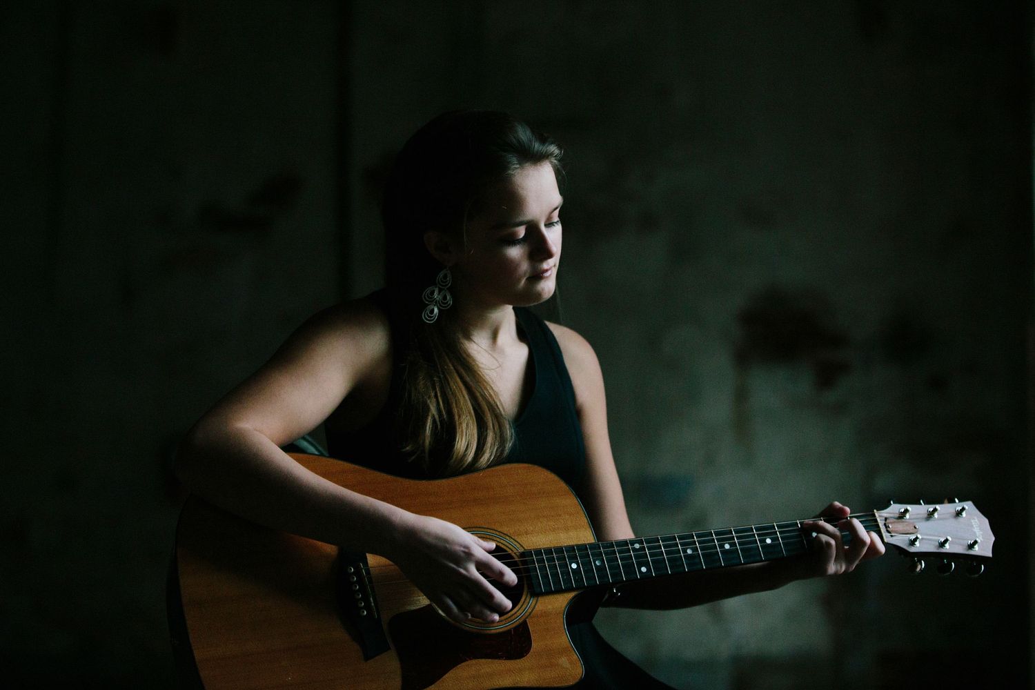 Moody portrait of a creative young woman playing guitar