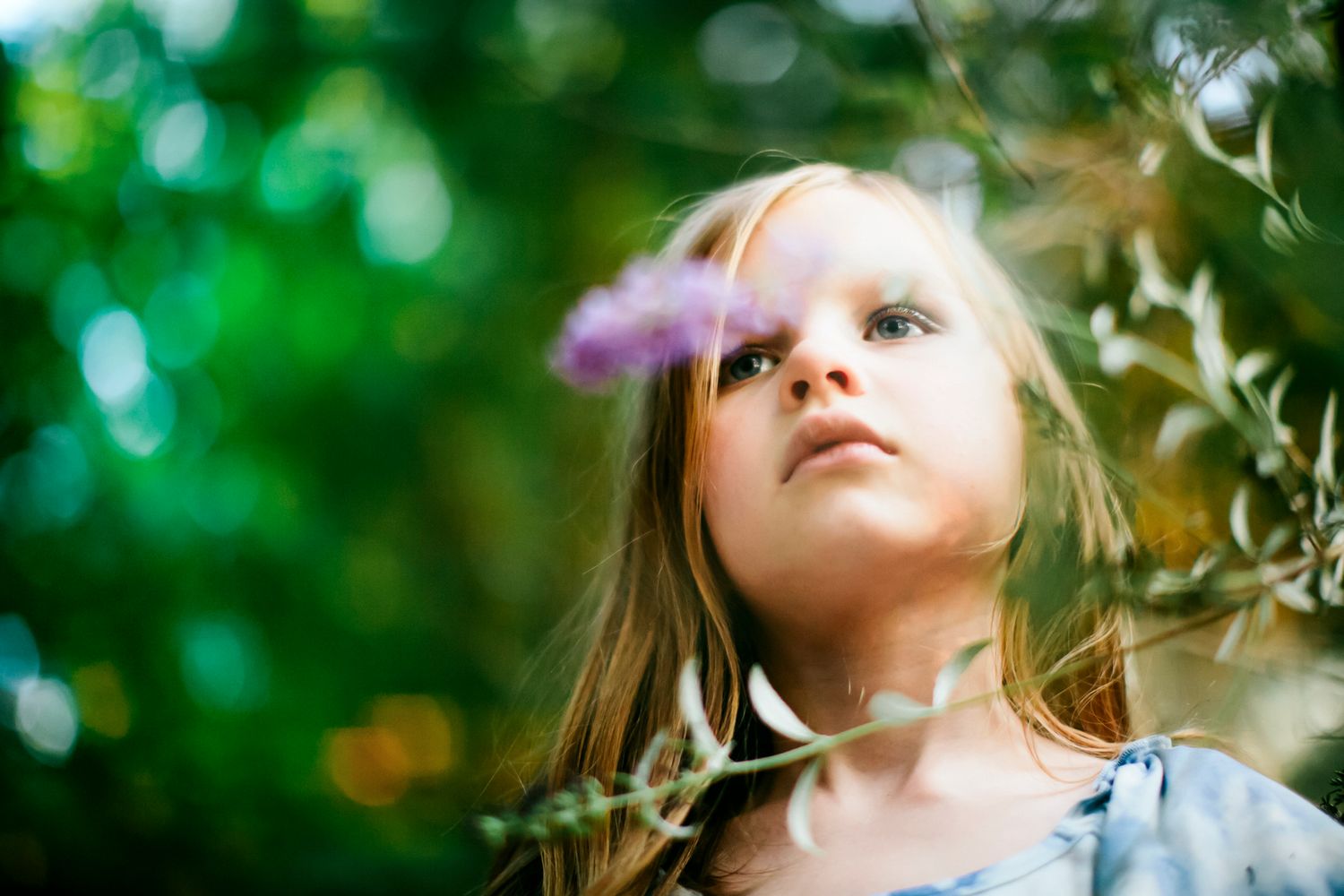 Moody portrait of little girl in the woods with flowers