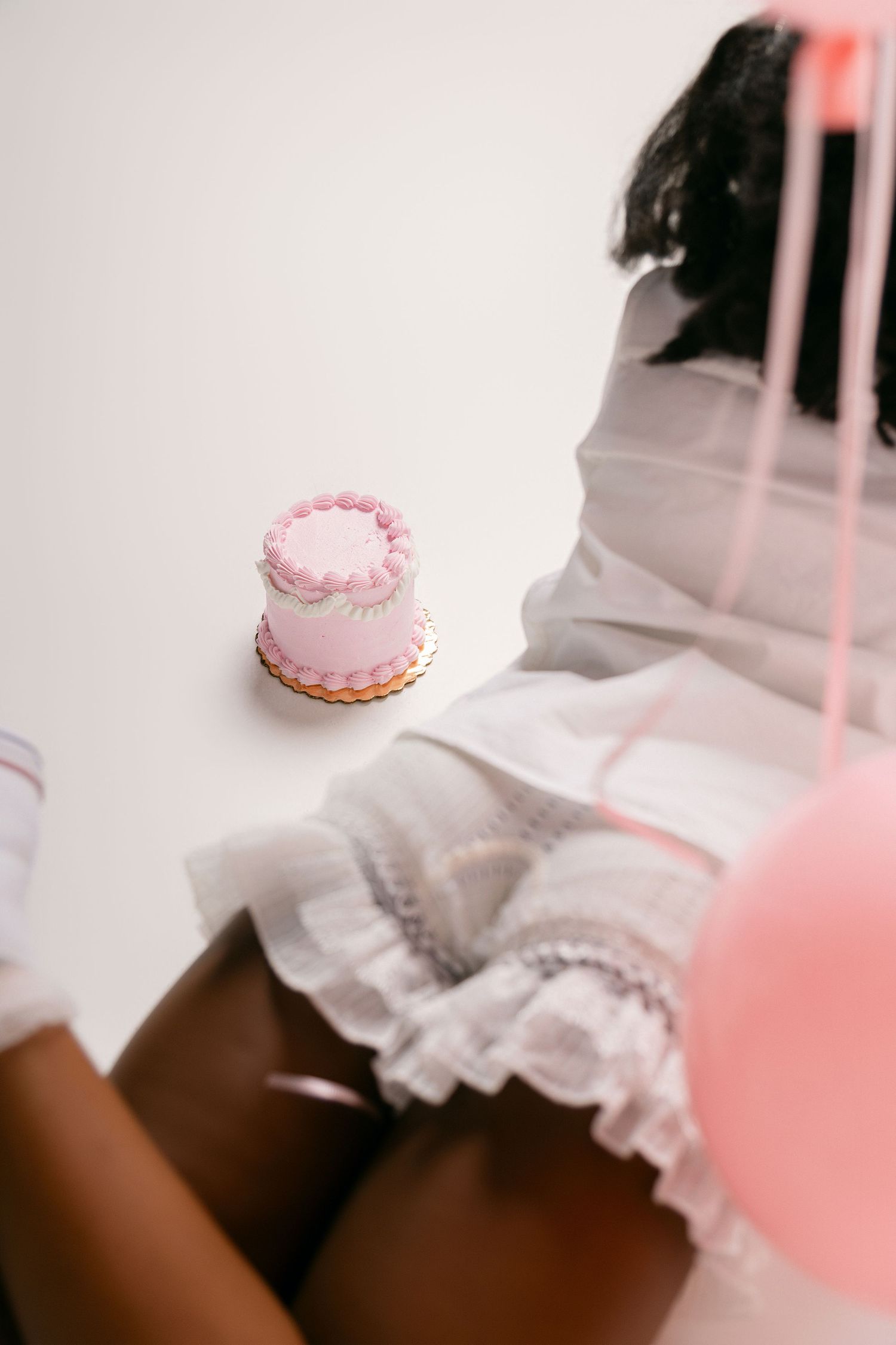 White ruffled fabric and pink decorative elements create a soft, romantic aesthetic composition.