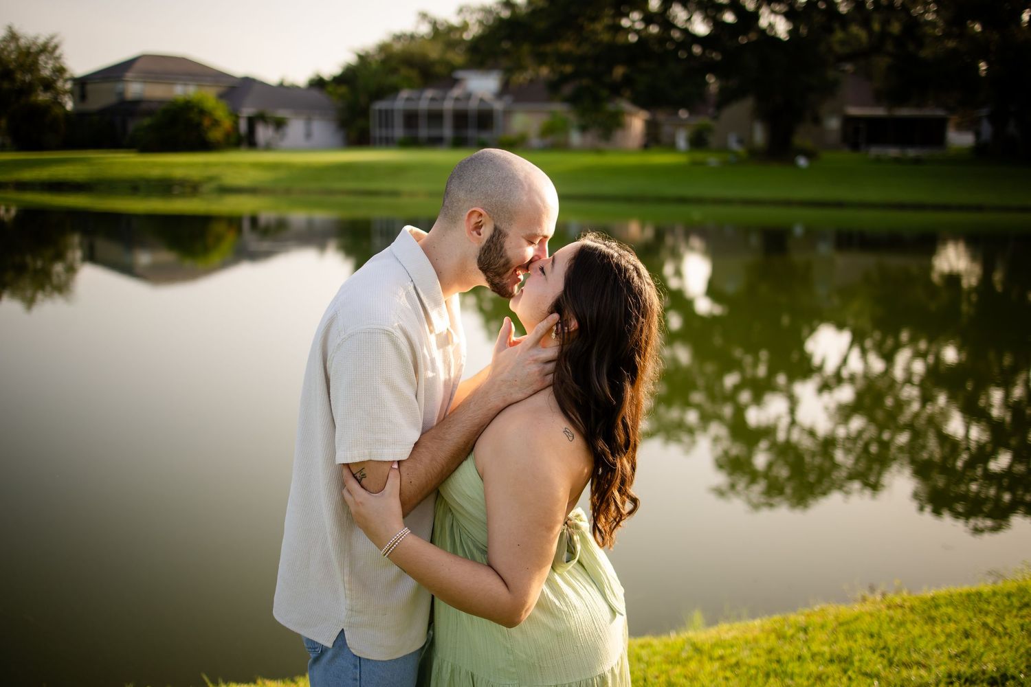 Romantic couple shares intimate moments together by a serene lakeside at sunset during a photo session.