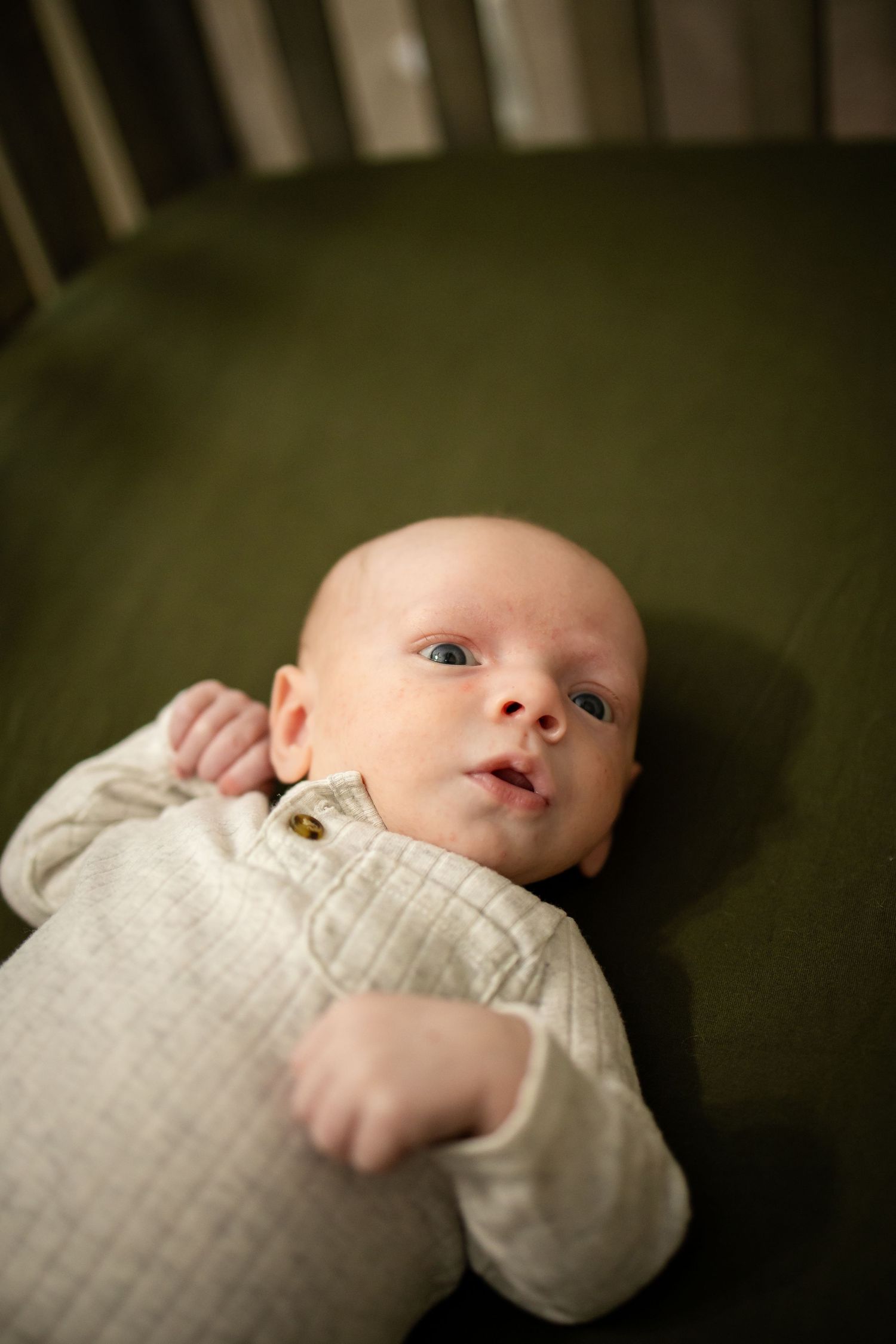 A small baby in a white garment lying down against a dark background.