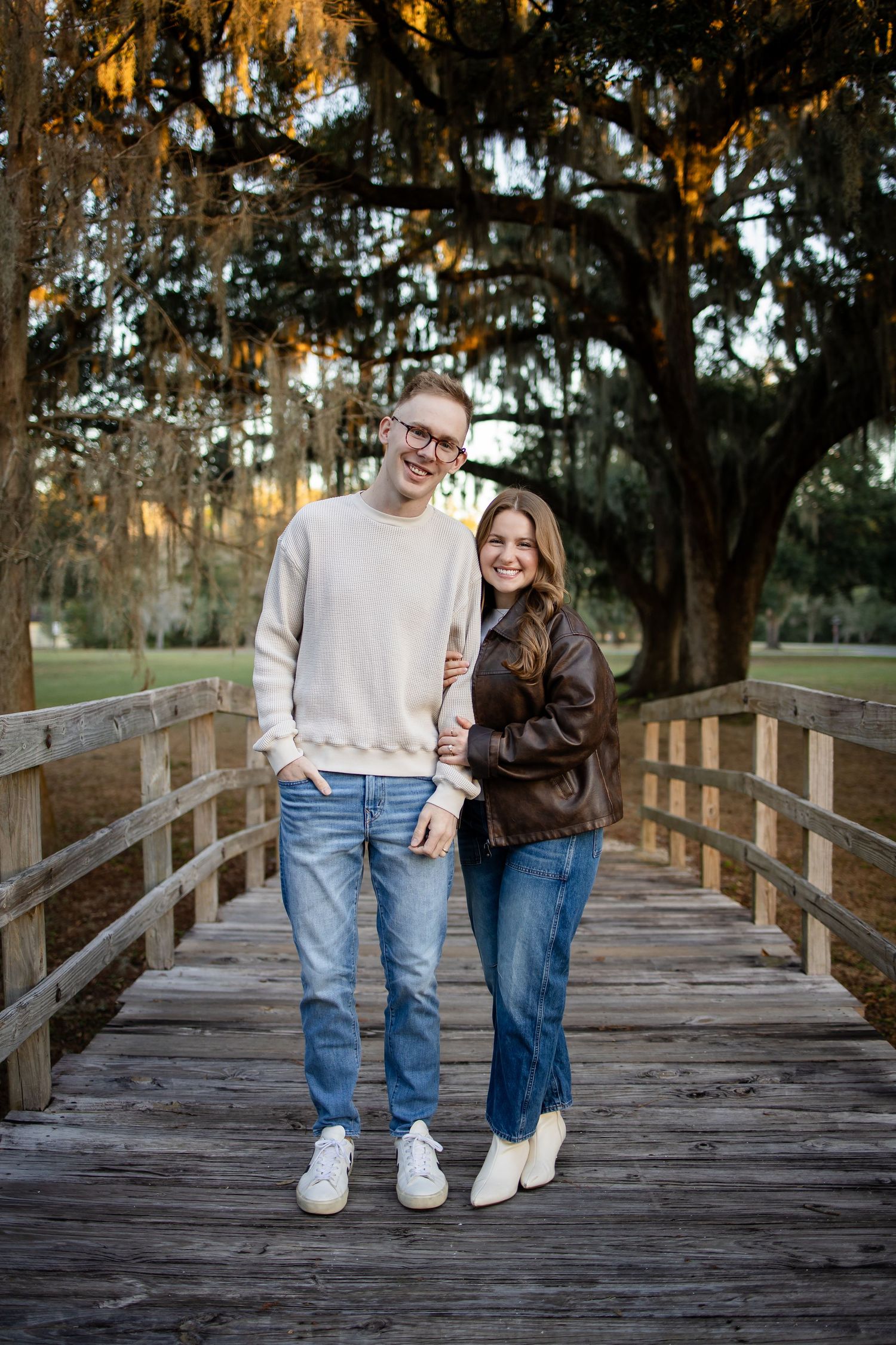 Couple walking hand in hand on a rustic wooden boardwalk through nature.
