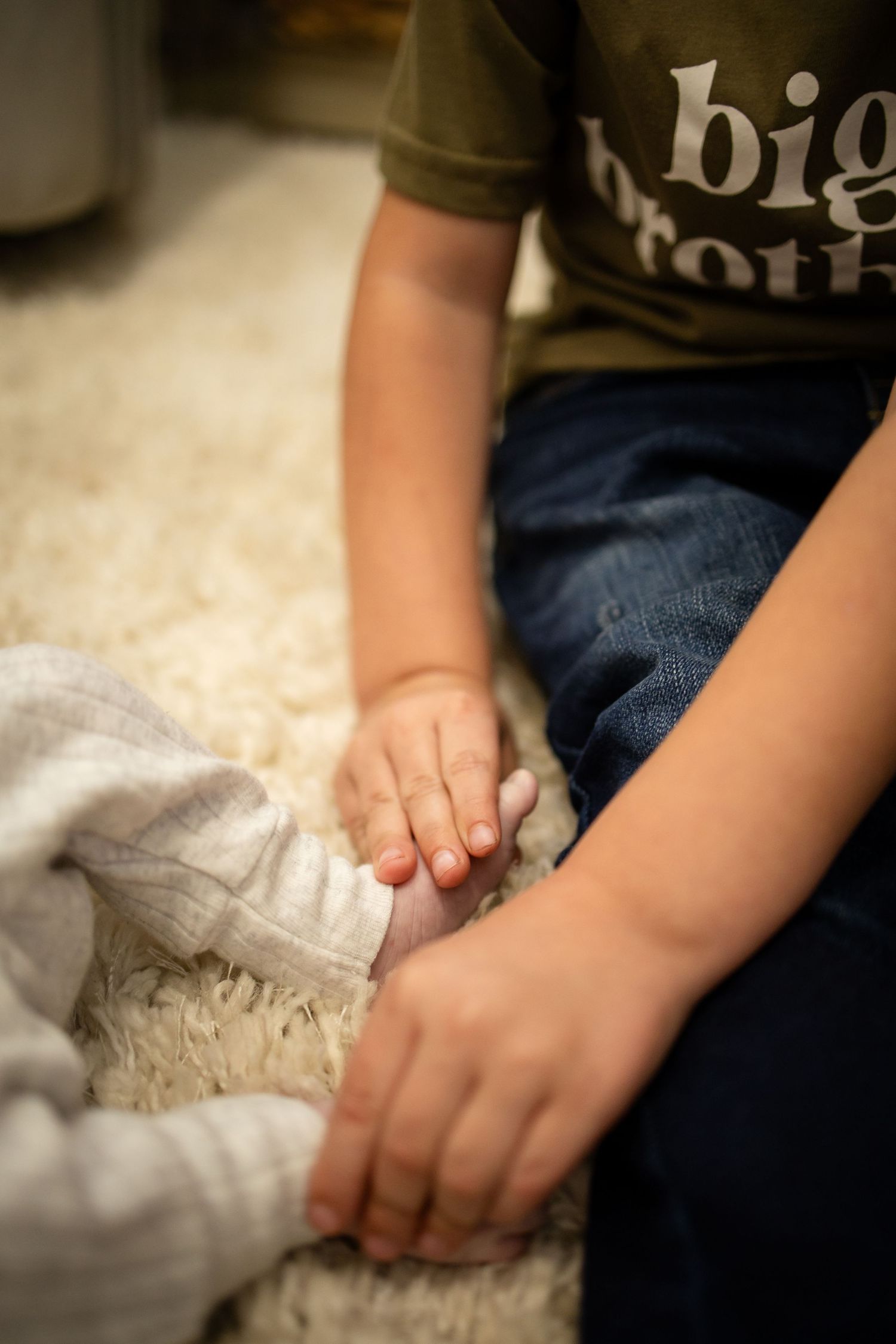 Gentle hands touching a white lace blanket while wearing a dark t-shirt and jeans in a soft focused photo.