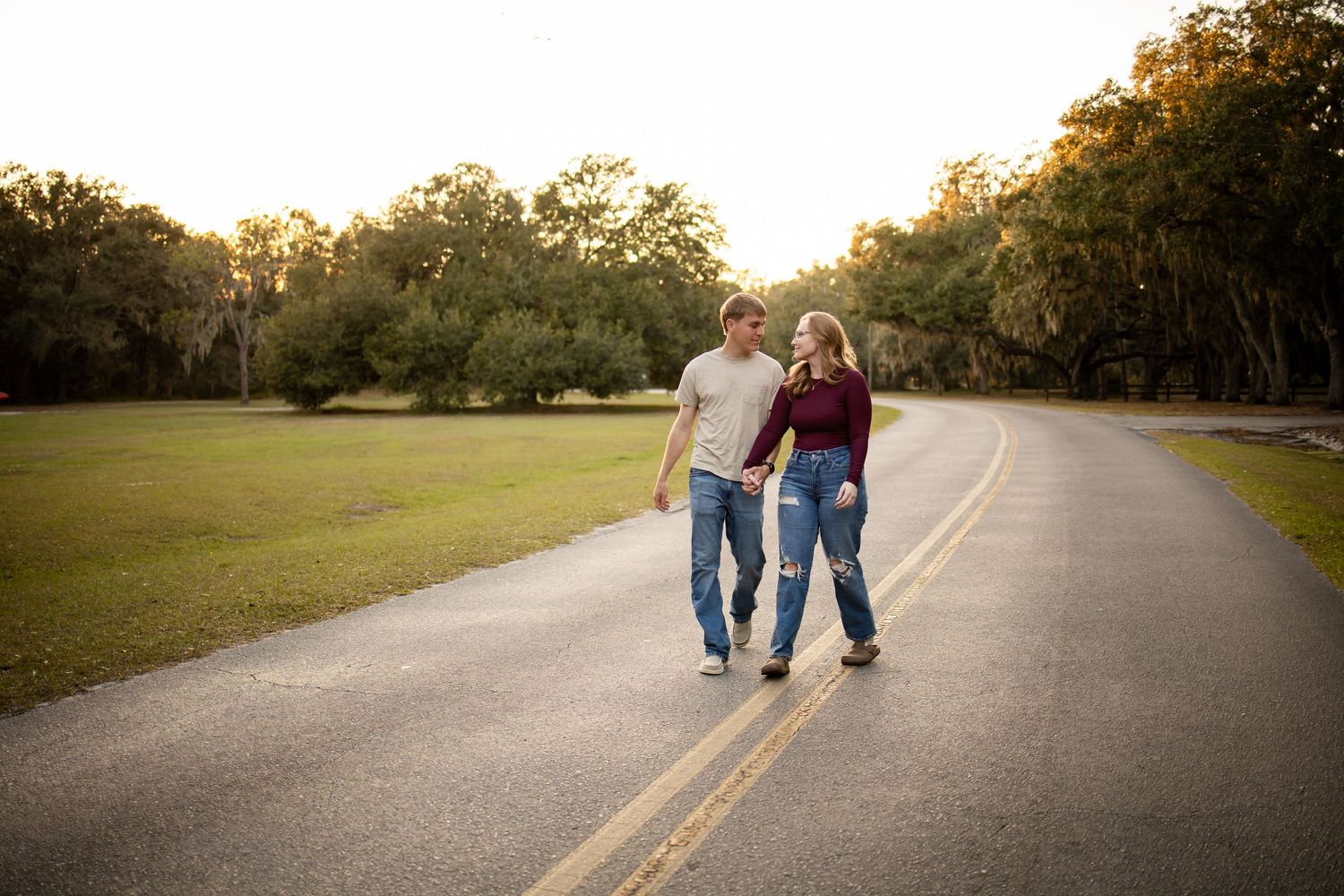 A couple strolling down a quiet country road during golden hour.