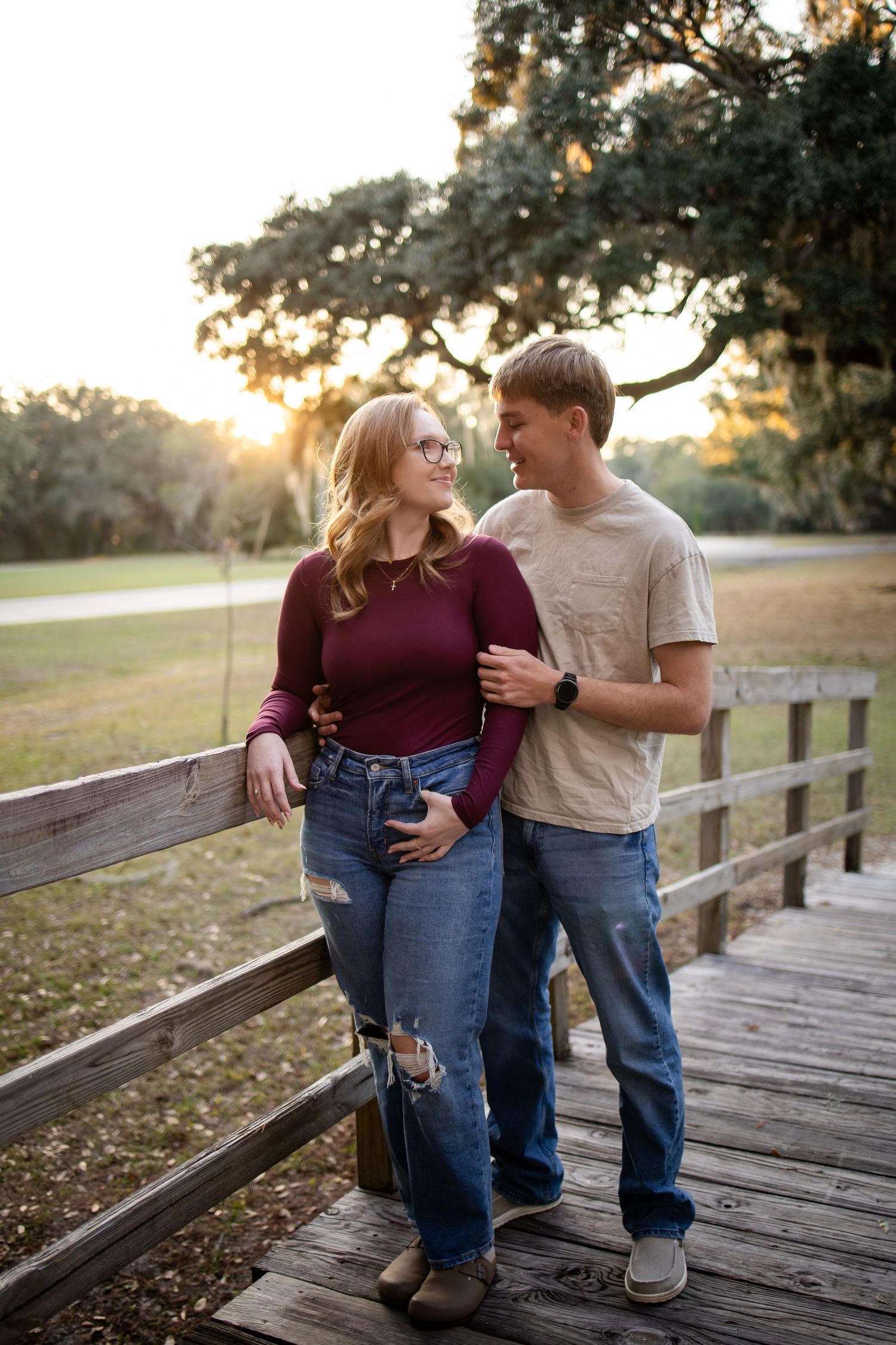 Romantic moment shared on a wooden bridge in a park during golden hour.