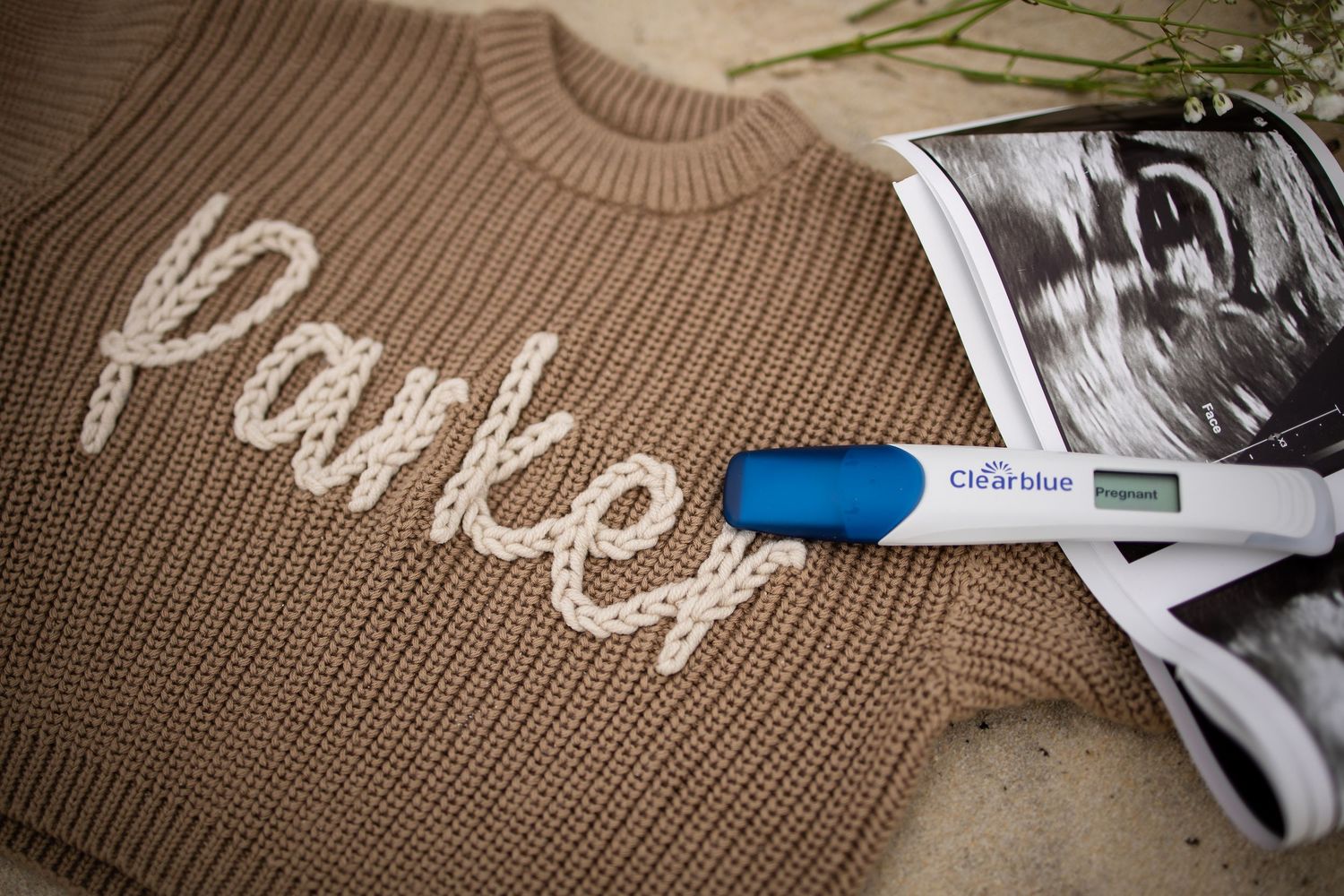 Close-up detail of a brown knit sweater or textile with white embroidered text.