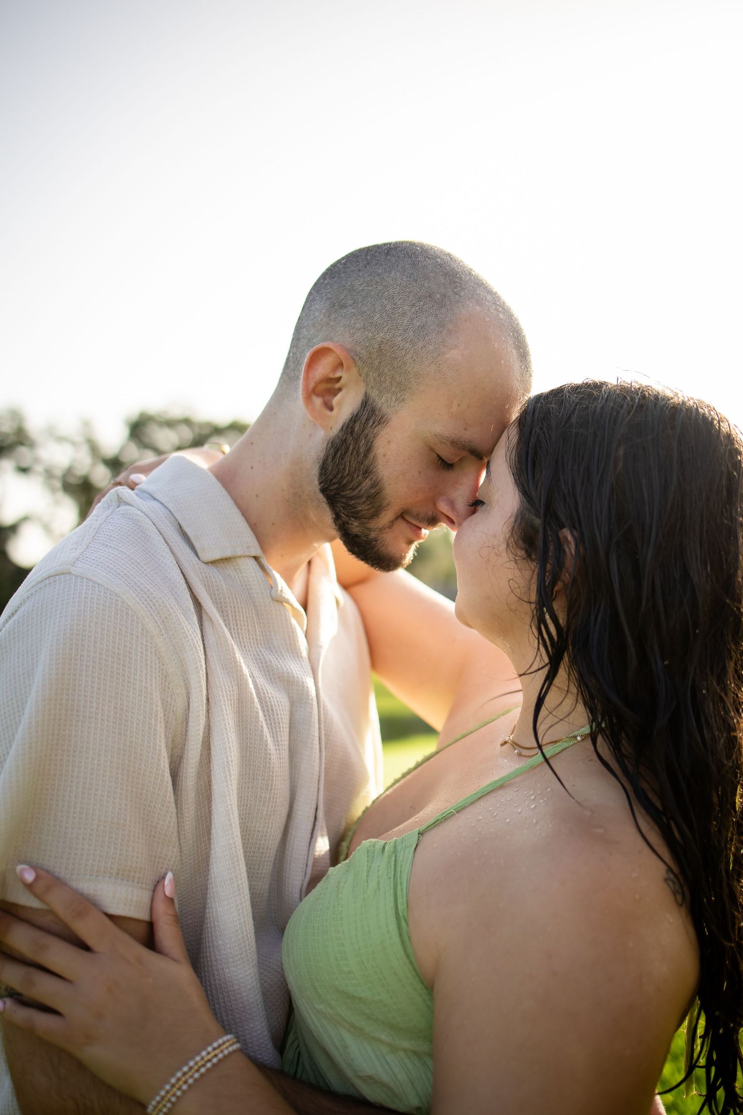 A romantic couple shares an intimate moment at sunset, with warm golden light illuminating their tender embrace.