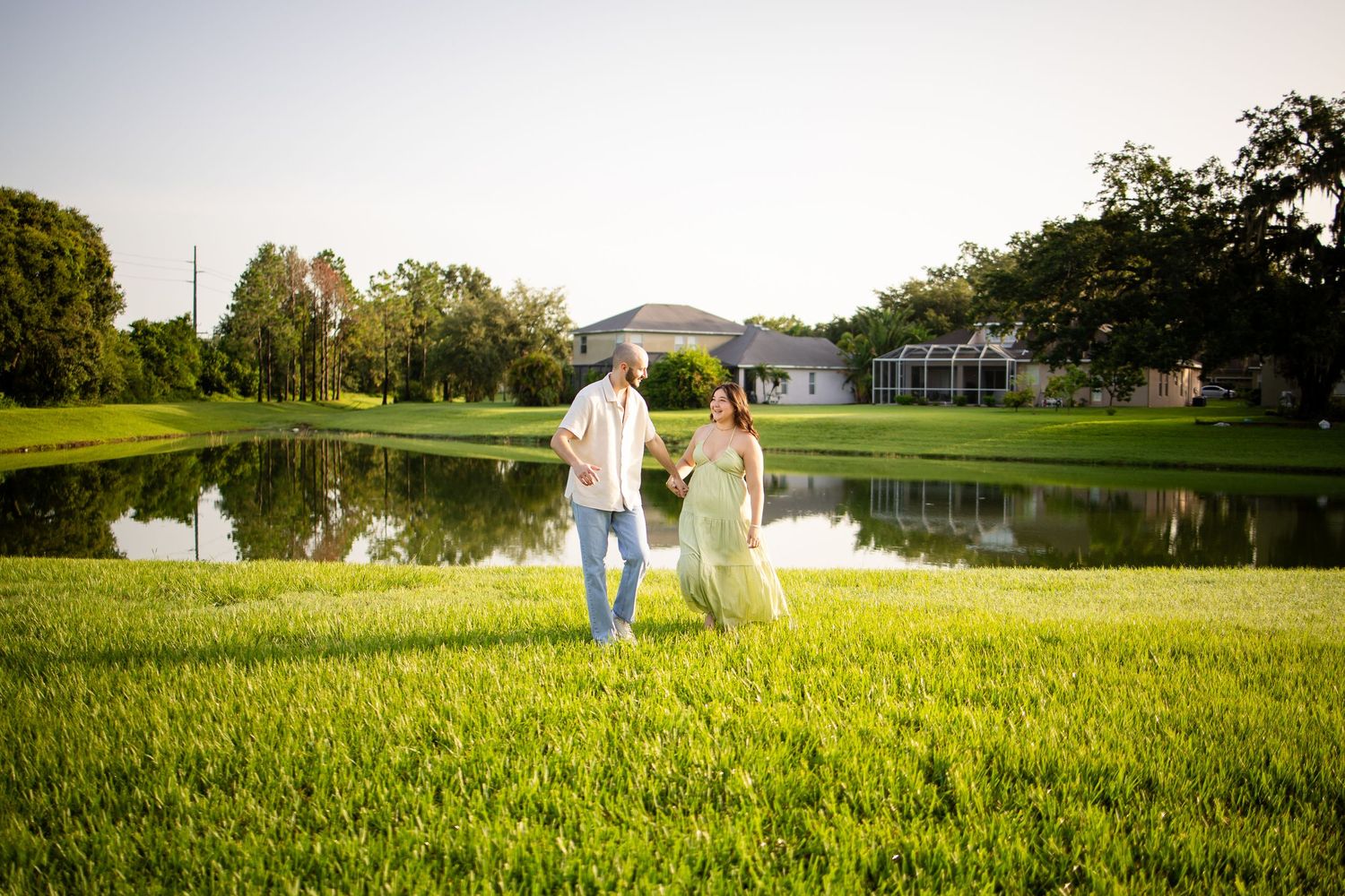 People in flowing white outfits walk through a lush green field on a sunny summer day.