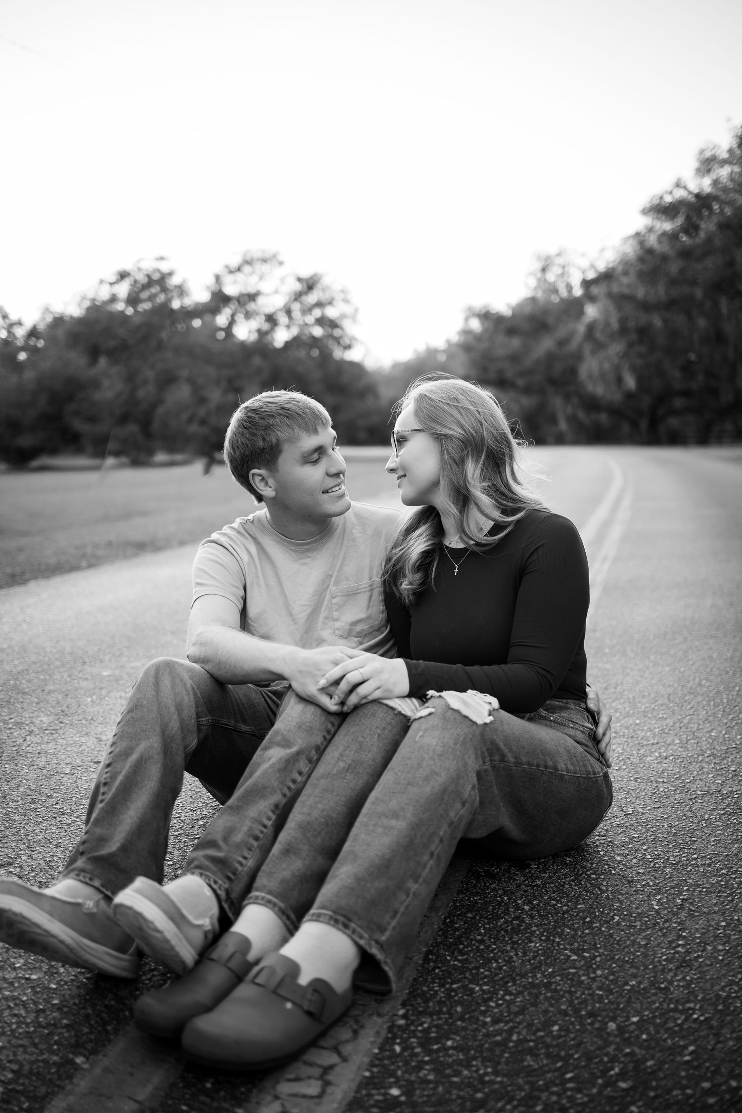 Black and white photo of couple sharing romantic moments on an empty road.