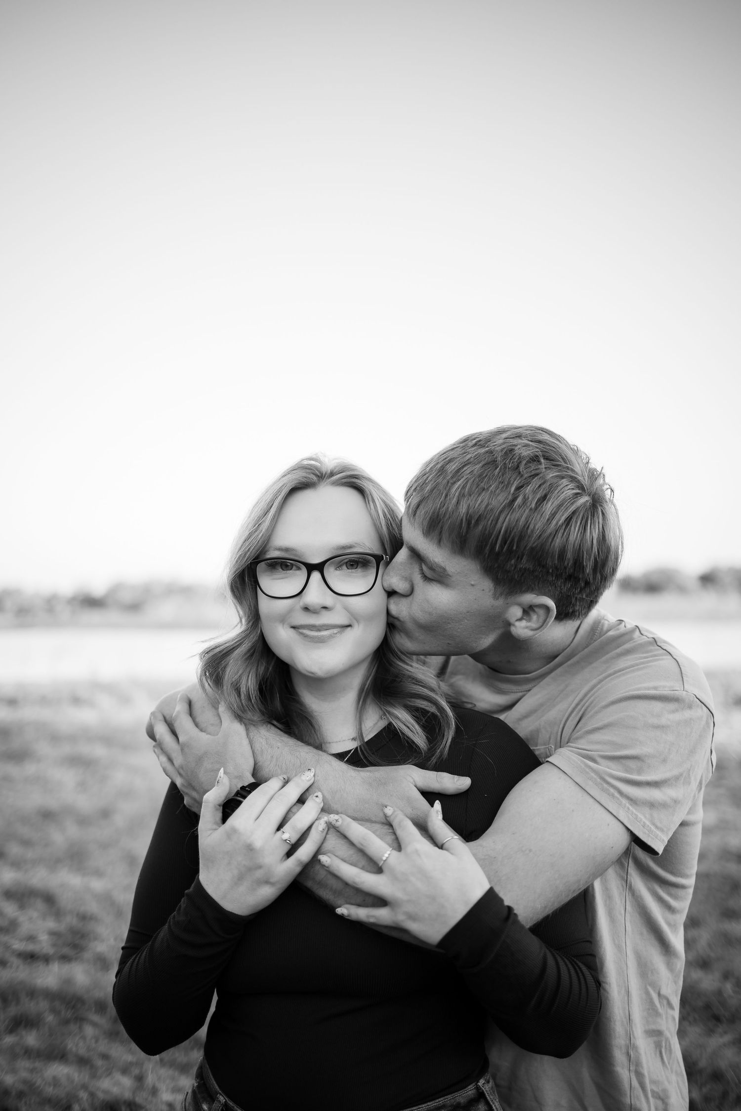 Black and white portrait of a couple sharing an intimate embrace outdoors.