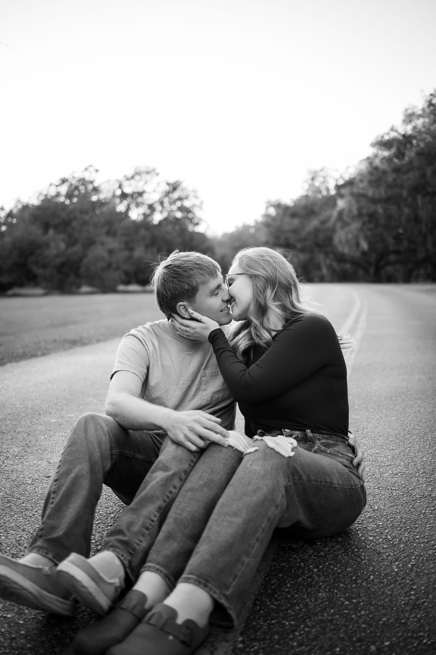 Couple lying together on ground sharing an intimate moment in black and white photography.