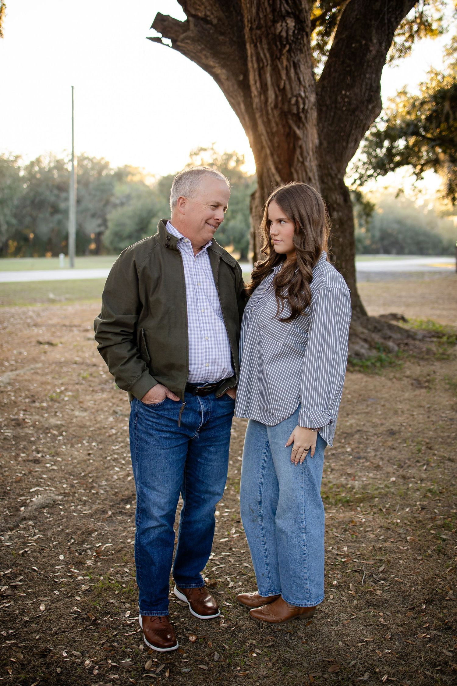 A playful outdoor photo series showing a couple in casual attire posing against trees at sunset.