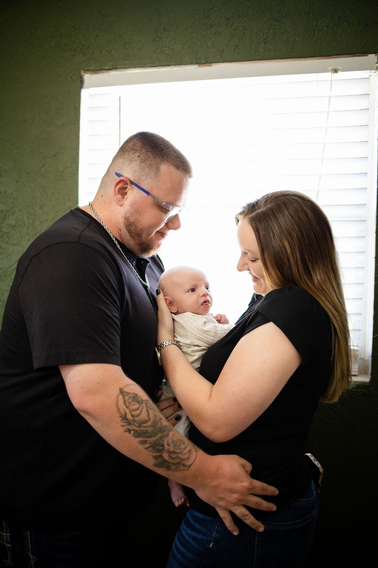 A tender family moment is captured in a sequence of intimate photos against a dark green wall and window light.