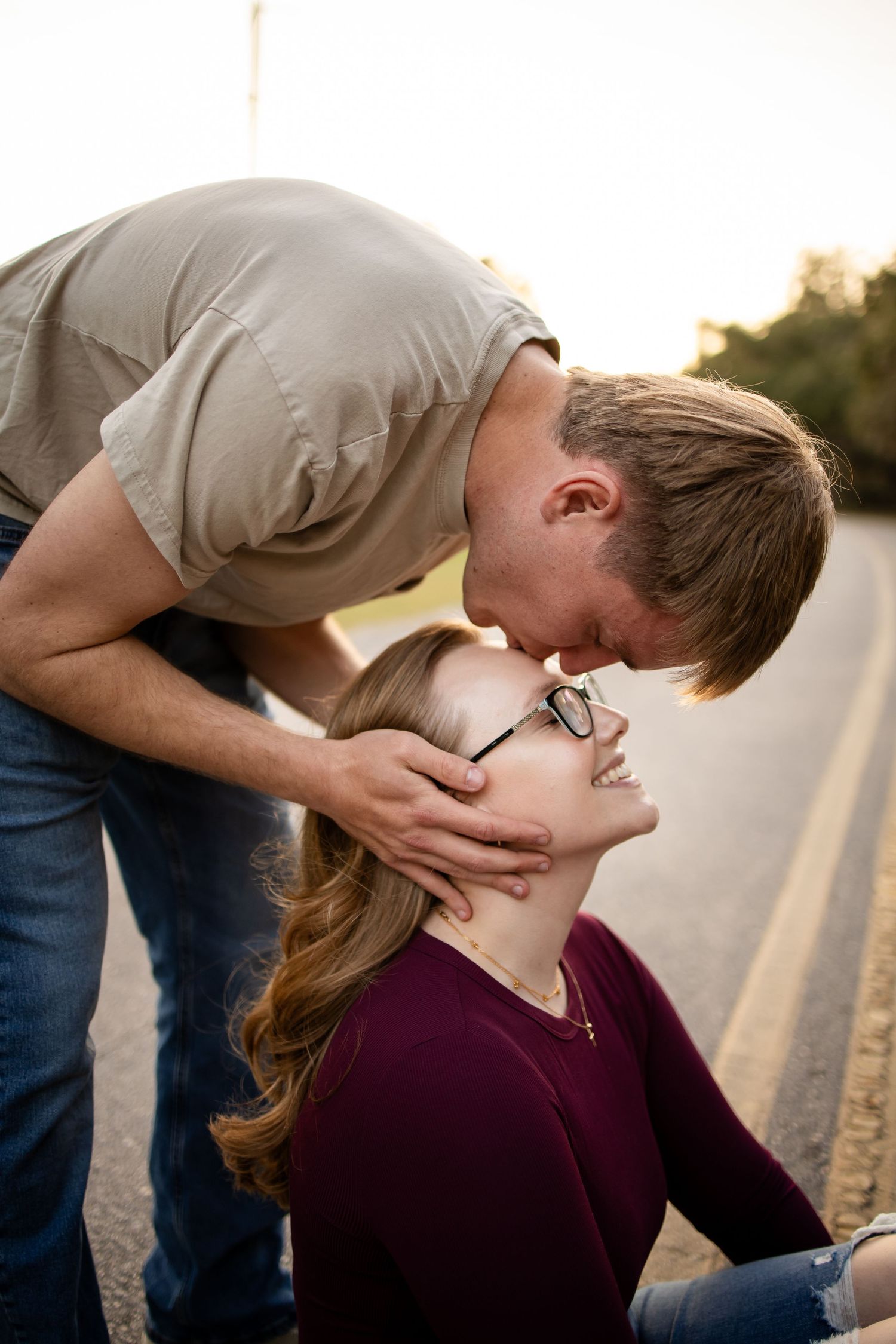 A sweet romantic moment shared between a couple on a sunlit road.