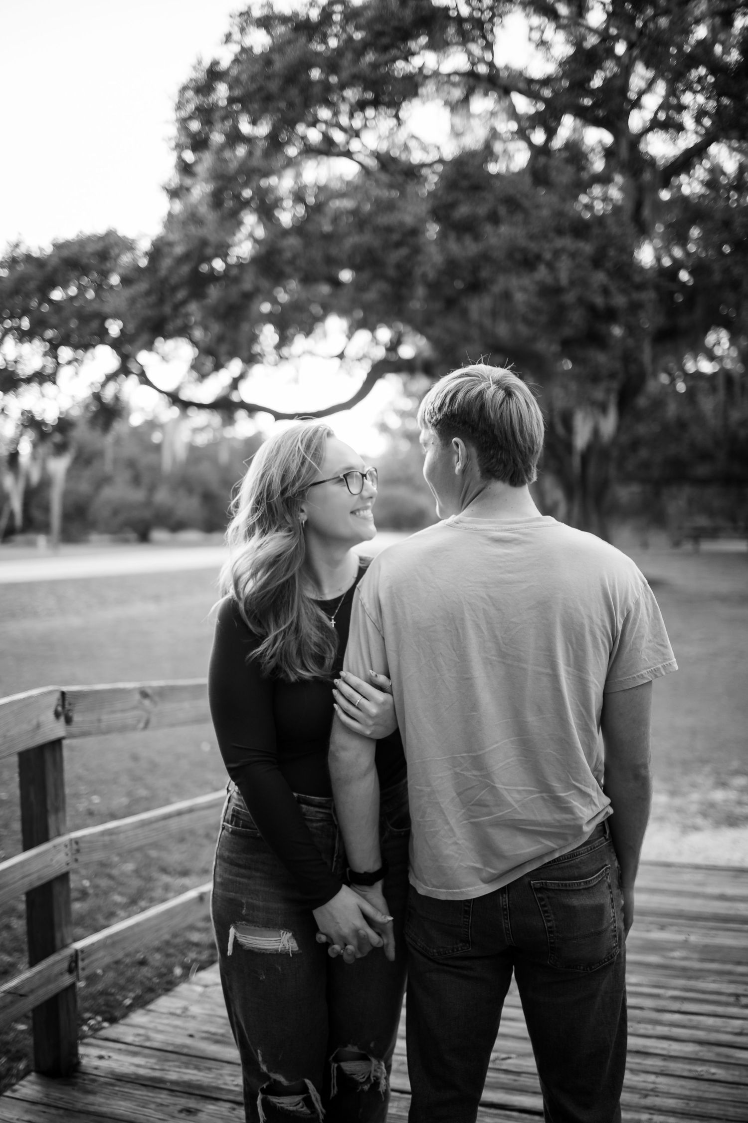 A couple walks together on a wooden boardwalk during sunset in black and white.
