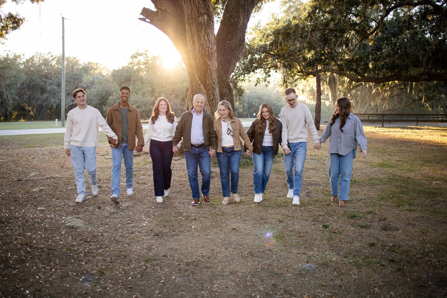 Group walking together on a path through autumn trees during sunset.
