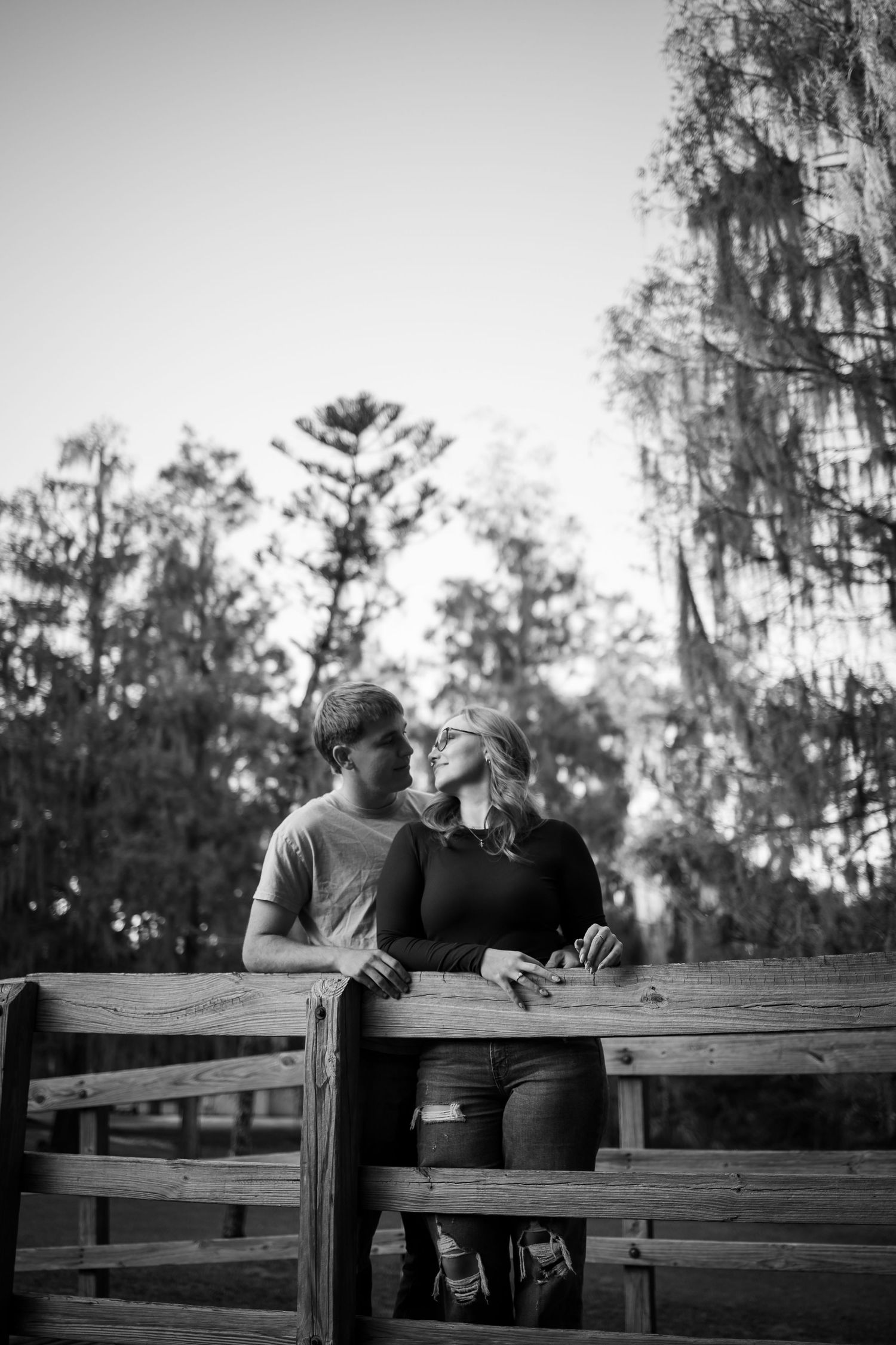 Couple sitting together on a wooden fence sharing an intimate moment.