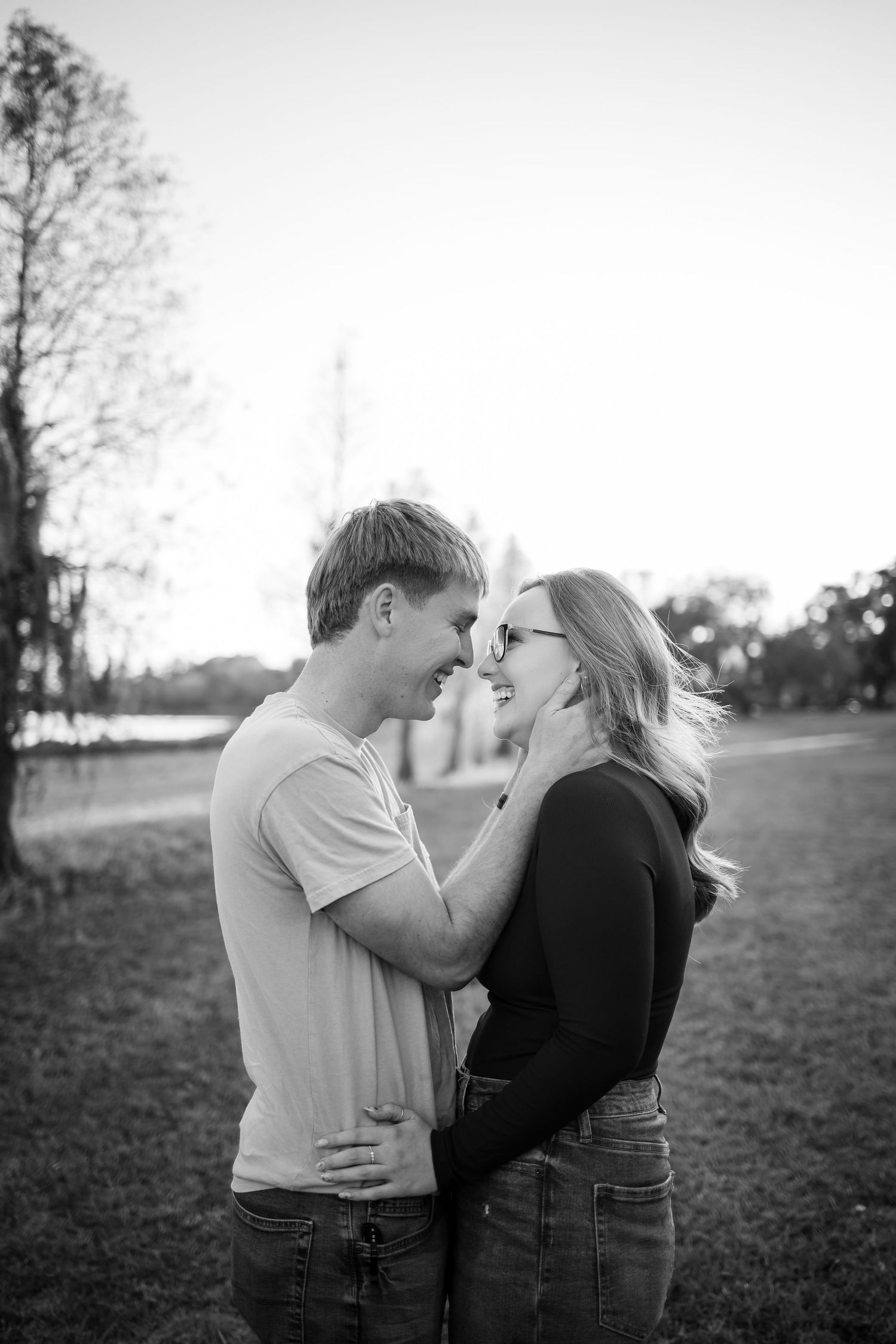 Black and white photo of a couple sharing a romantic moment in an open field.