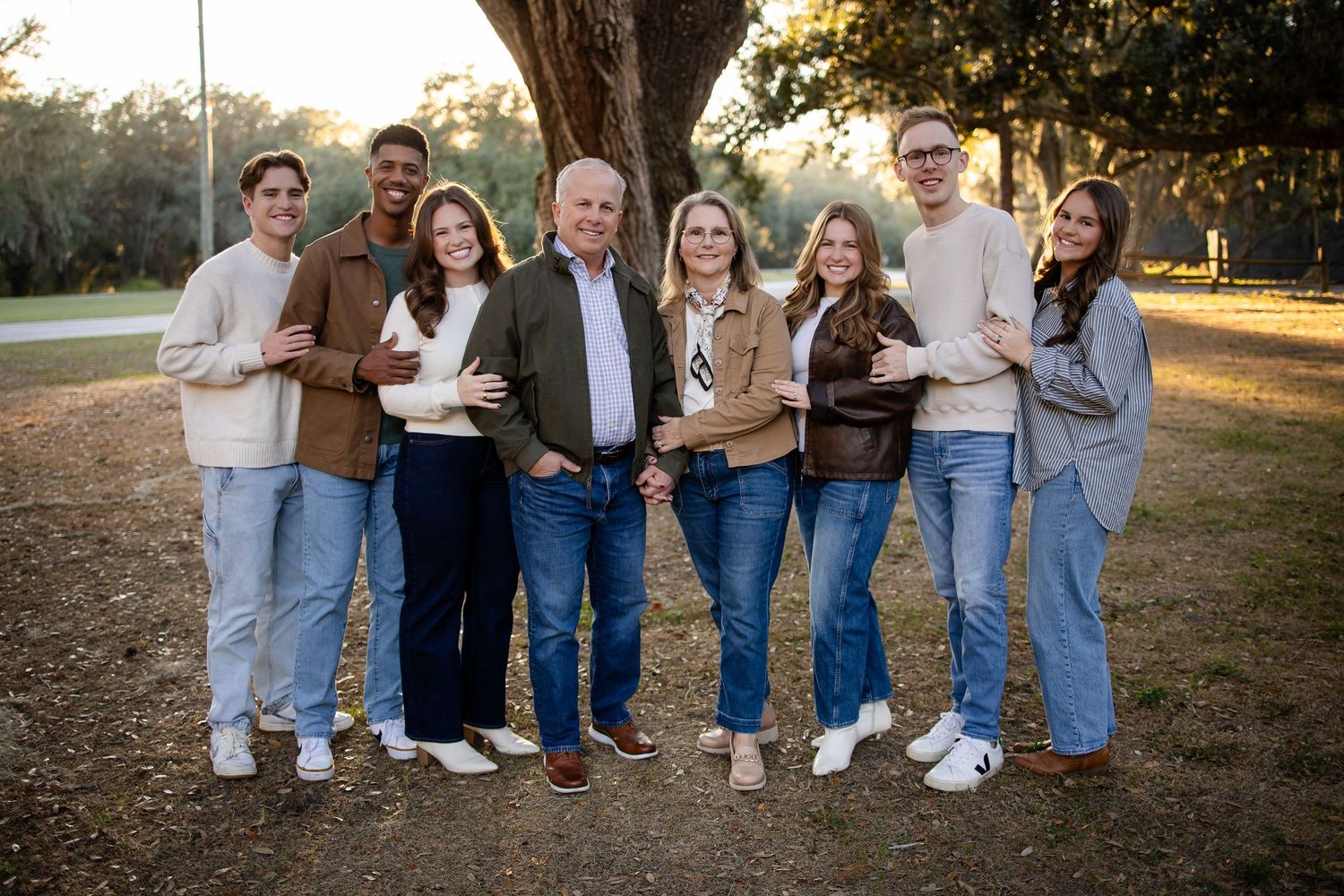 Friends in coordinated denim and neutral outfits posing together under a tree.