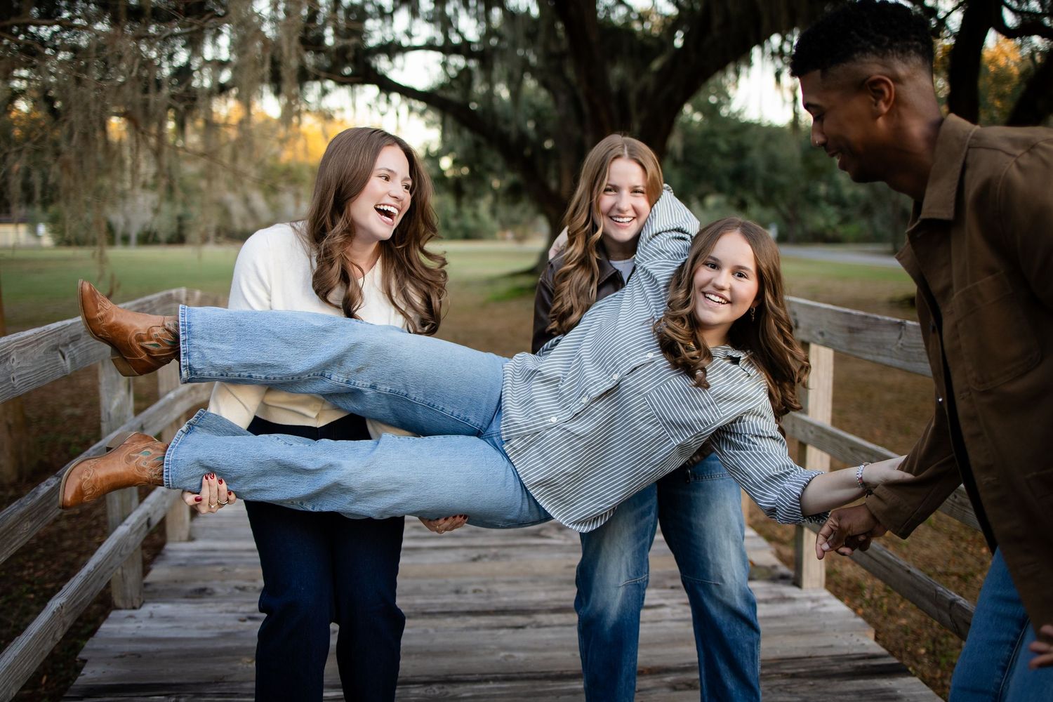 Friends having fun while carrying someone on a wooden bridge in a park.