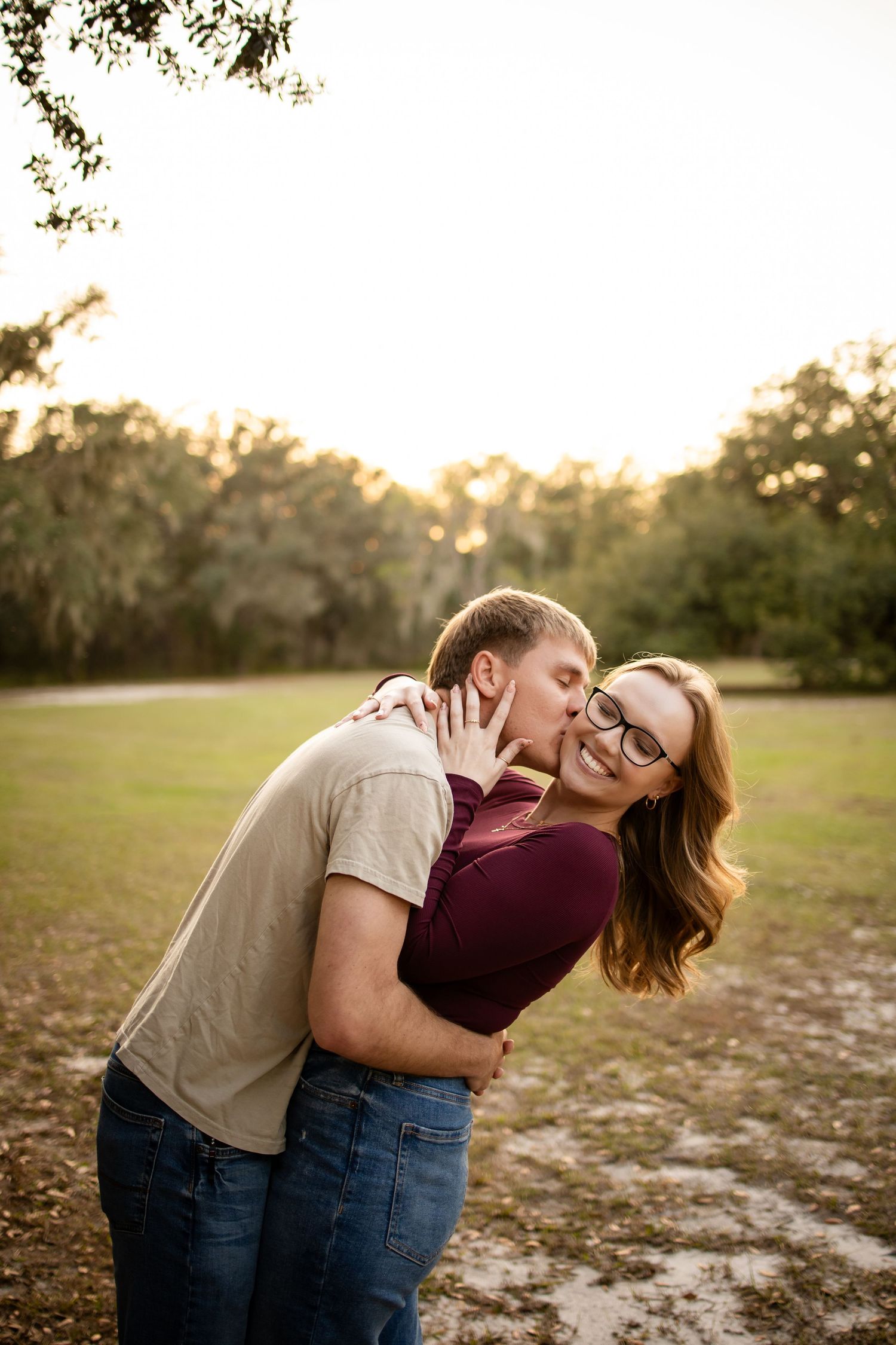 A couple shares a joyful embrace in a park during golden hour.