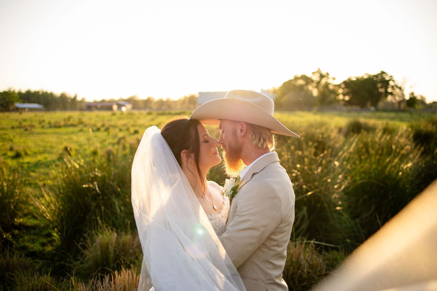 Romantic couple embracing in a sunlit field during sunset with dreamy golden light.