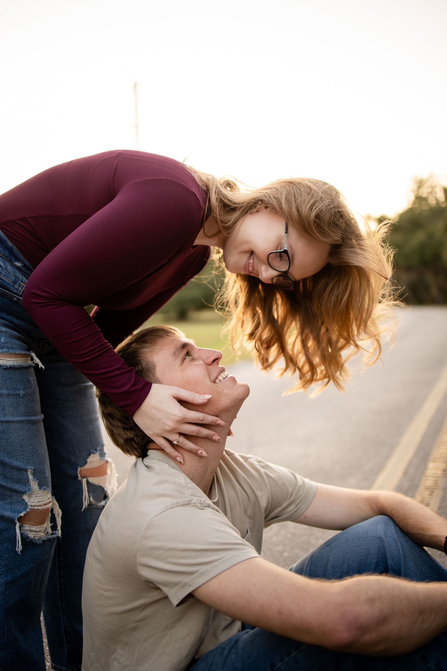 A playful moment captured between a couple on a rural road at sunset.