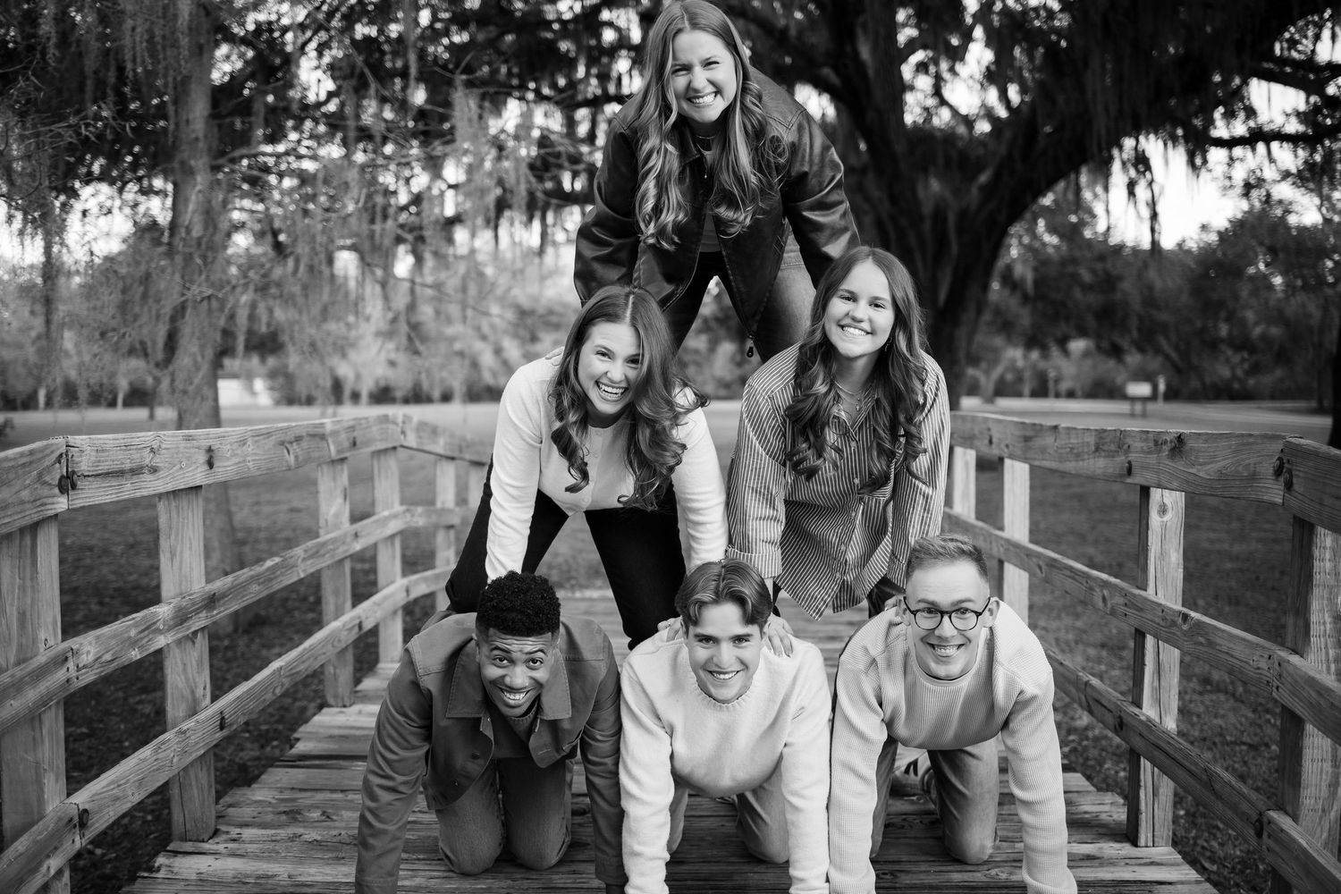 Group enjoying candid moments together on rustic wooden bridge during photo session.