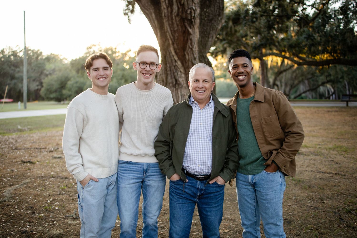 Casual group photo of people in coordinated outfits standing together under trees.