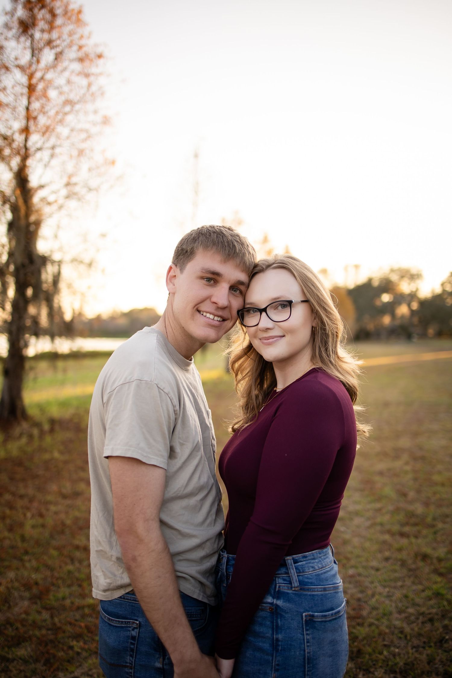 A couple shares a sweet moment together during golden hour in a grassy field.