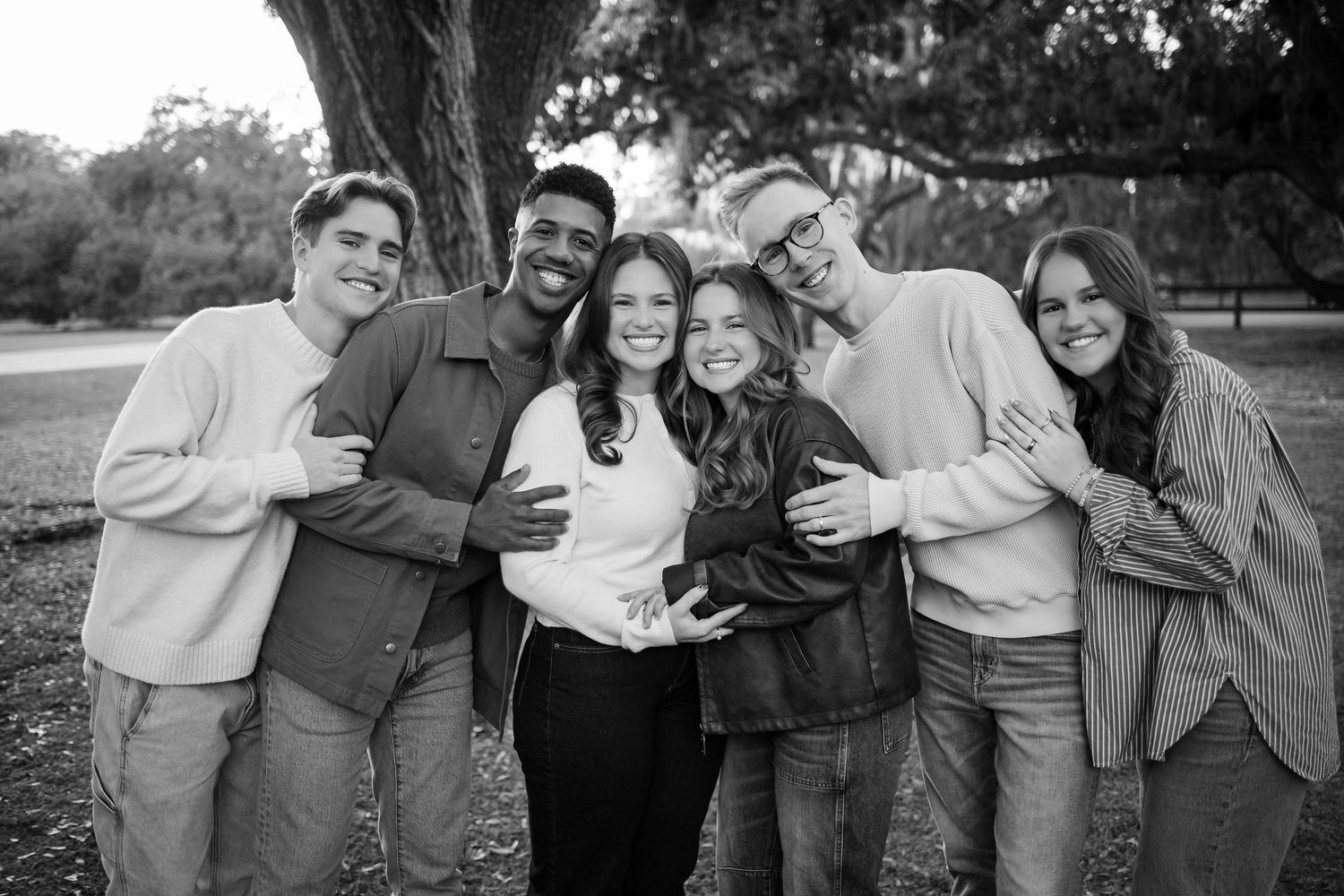 Black and white photo of a group laughing together outdoors.
