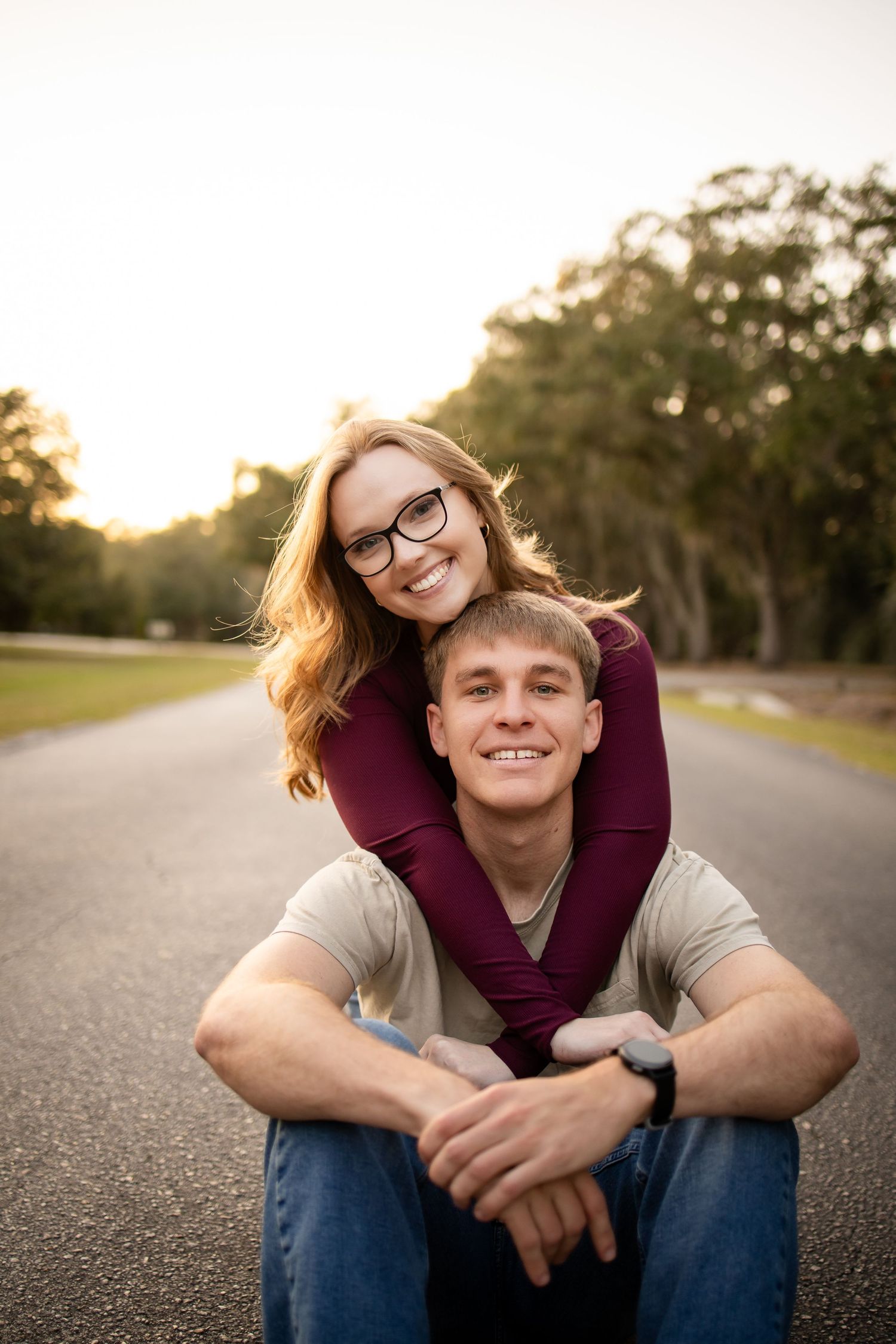 Happy couple sharing a relaxed moment on a paved road at sunset.